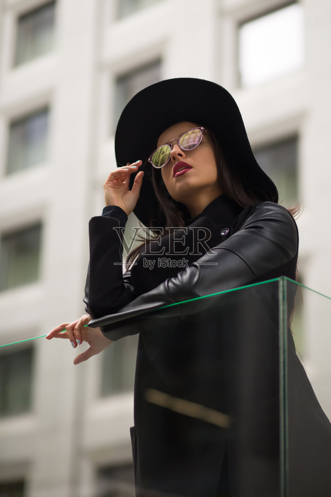 穿着时髦的年轻女子在宽边黑帽子和镜子太阳镜照片摄影图片