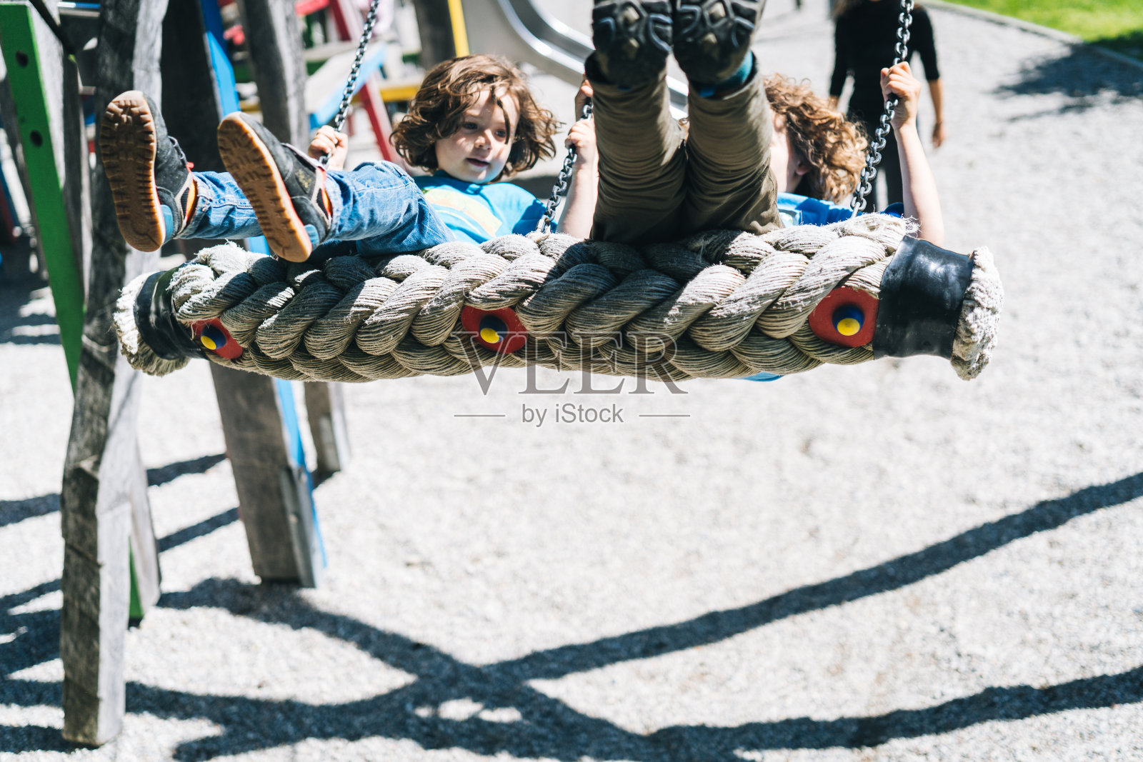 在操场上，母亲推着小男孩荡秋千照片摄影图片