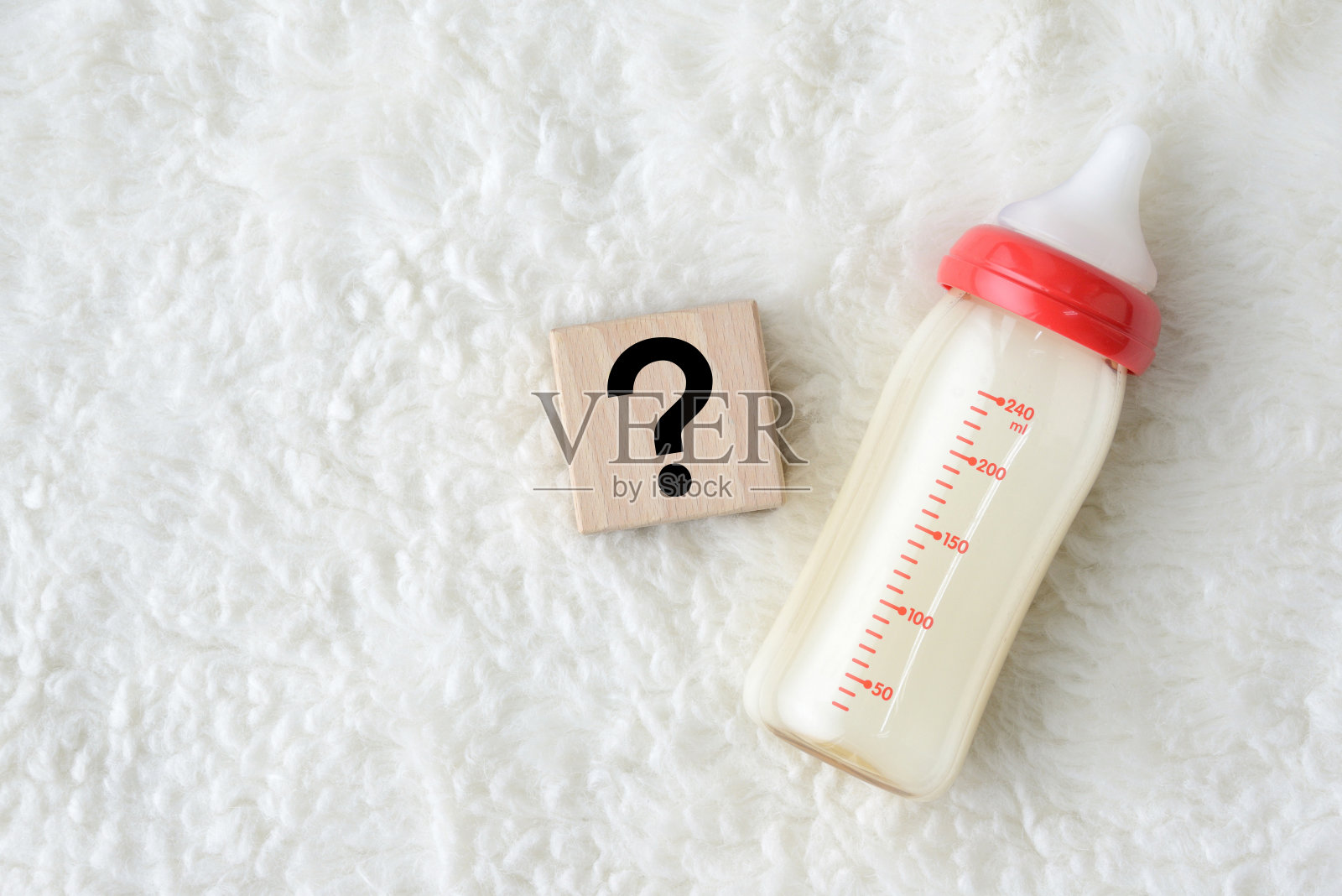 柔软地毯上的婴儿奶瓶和带问号的木块照片摄影图片