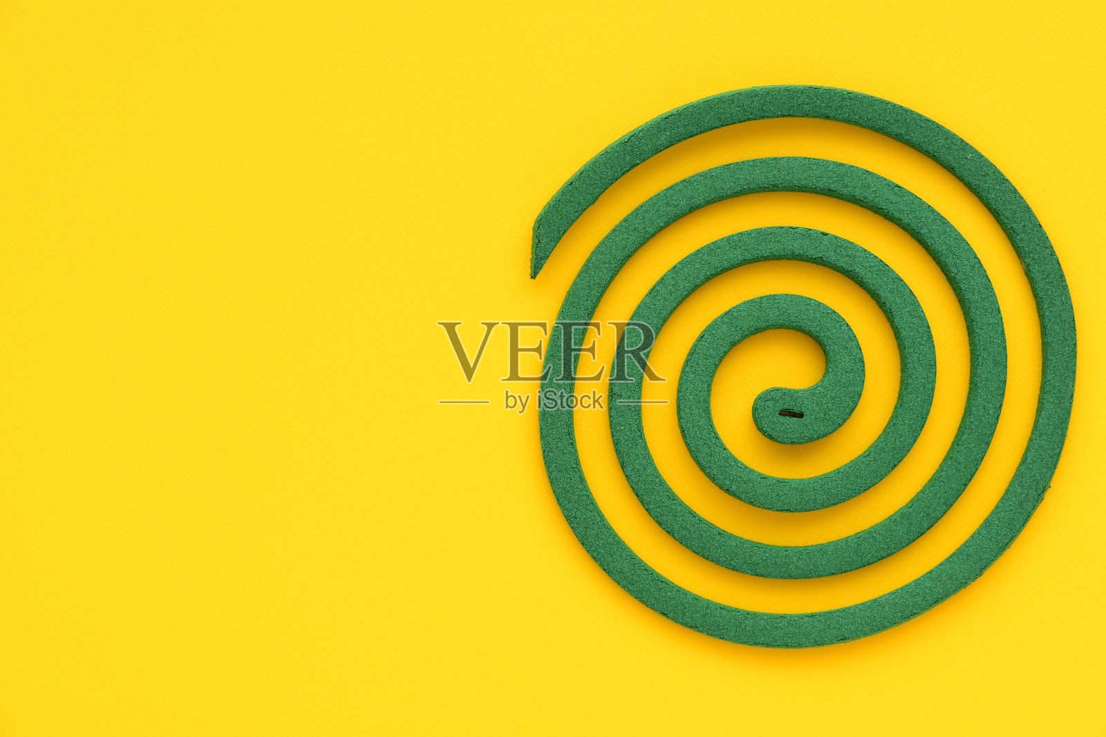 黄色背景上有绿色的蚊香。照片摄影图片