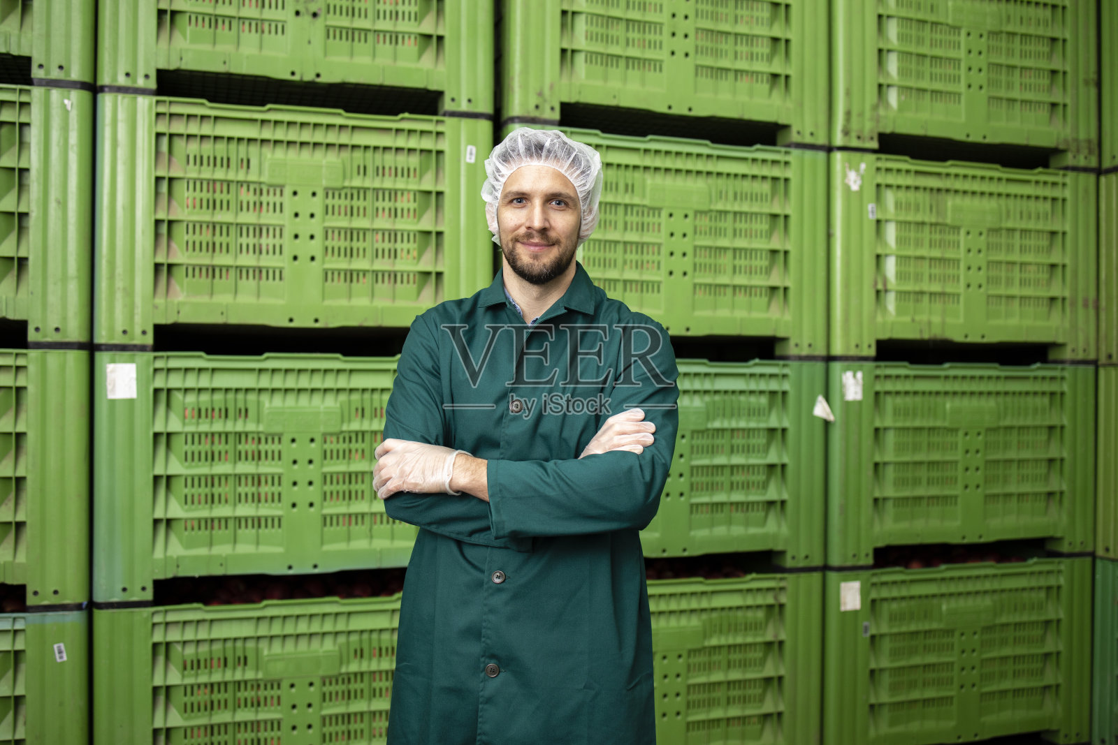 有机食品工厂仓库的工人站在苹果水果箱旁的肖像。照片摄影图片