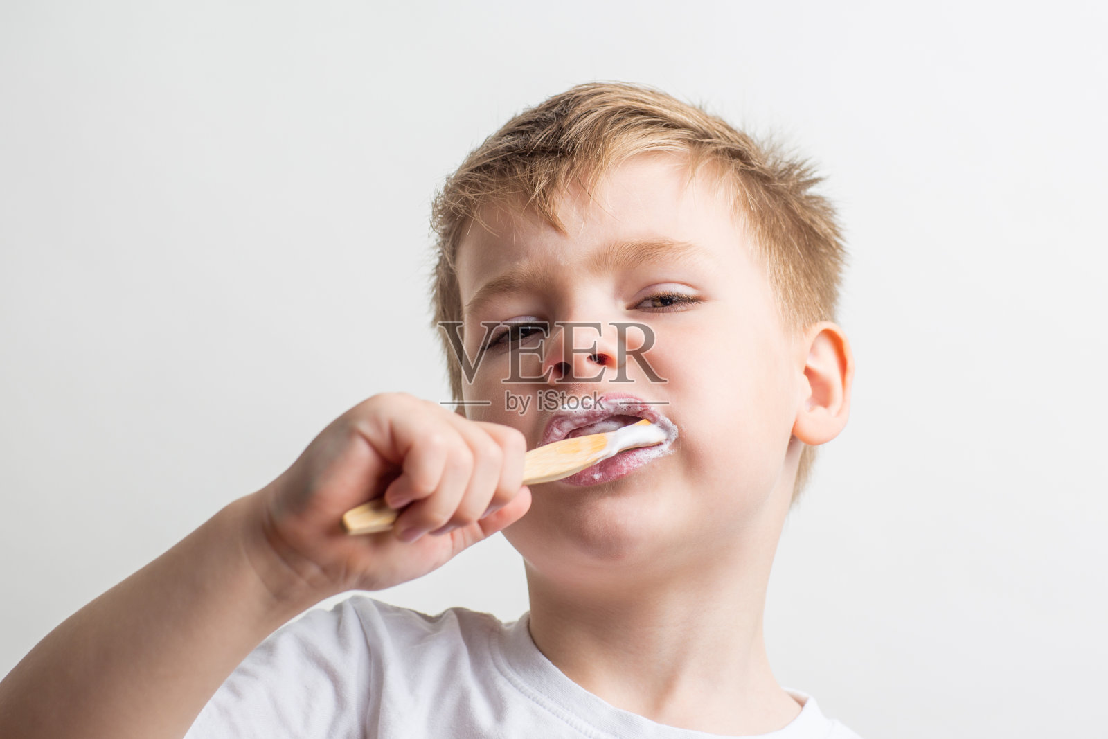 可爱的小男孩嘴里叼着竹牙刷，孩子在刷牙照片摄影图片