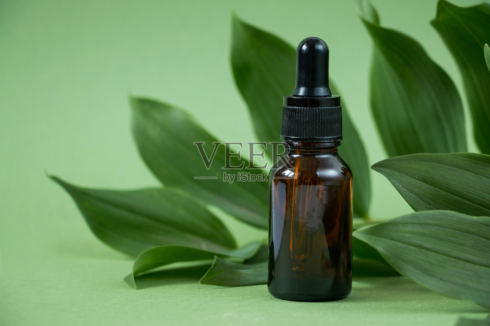 绿色背景的琥珀色玻璃化妆瓶。天然有机美容产品理念。水疗，皮肤护理，身体护理照片摄影图片