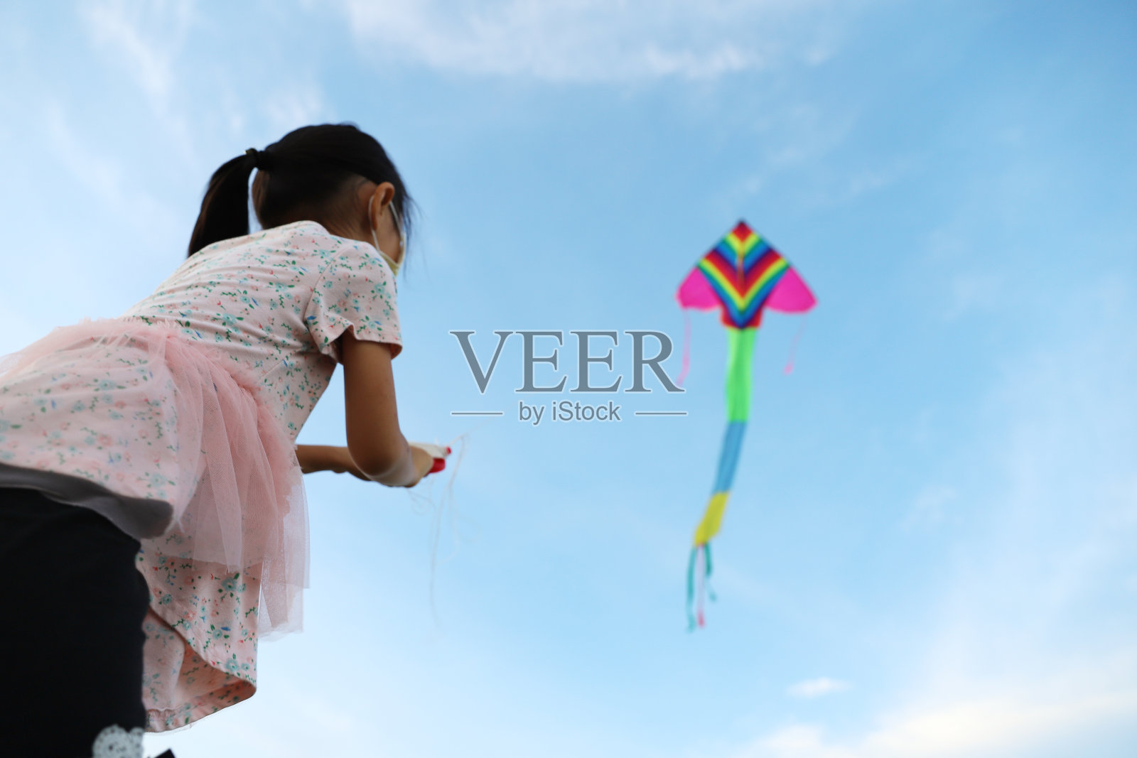 亚洲女孩在草地上玩和放风筝。照片摄影图片