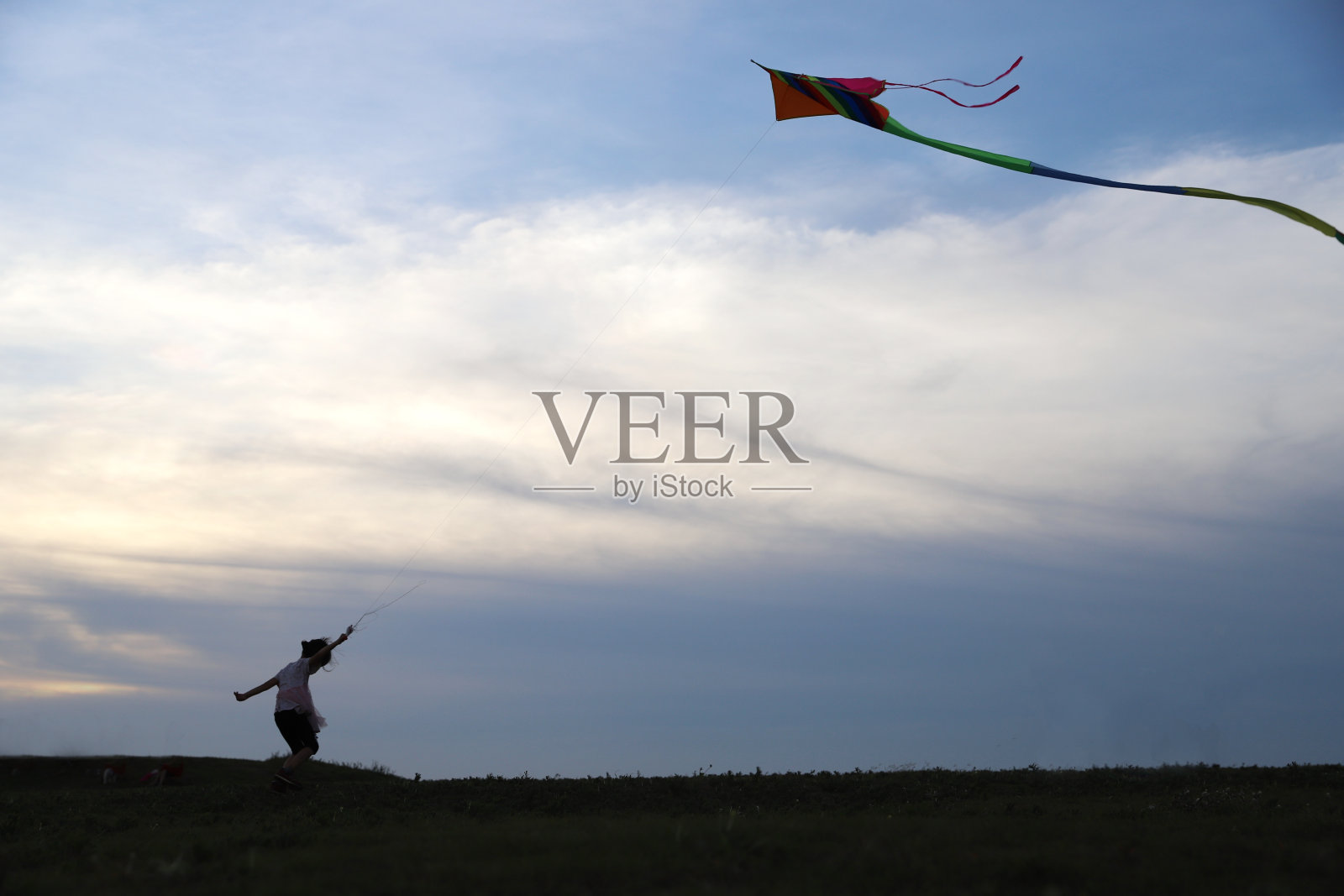 亚洲女孩在草地上玩和放风筝。照片摄影图片