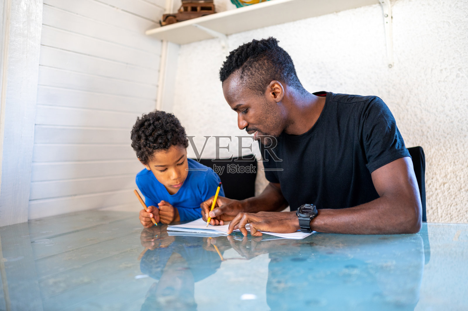 父子俩正坐在桌前做作业照片摄影图片