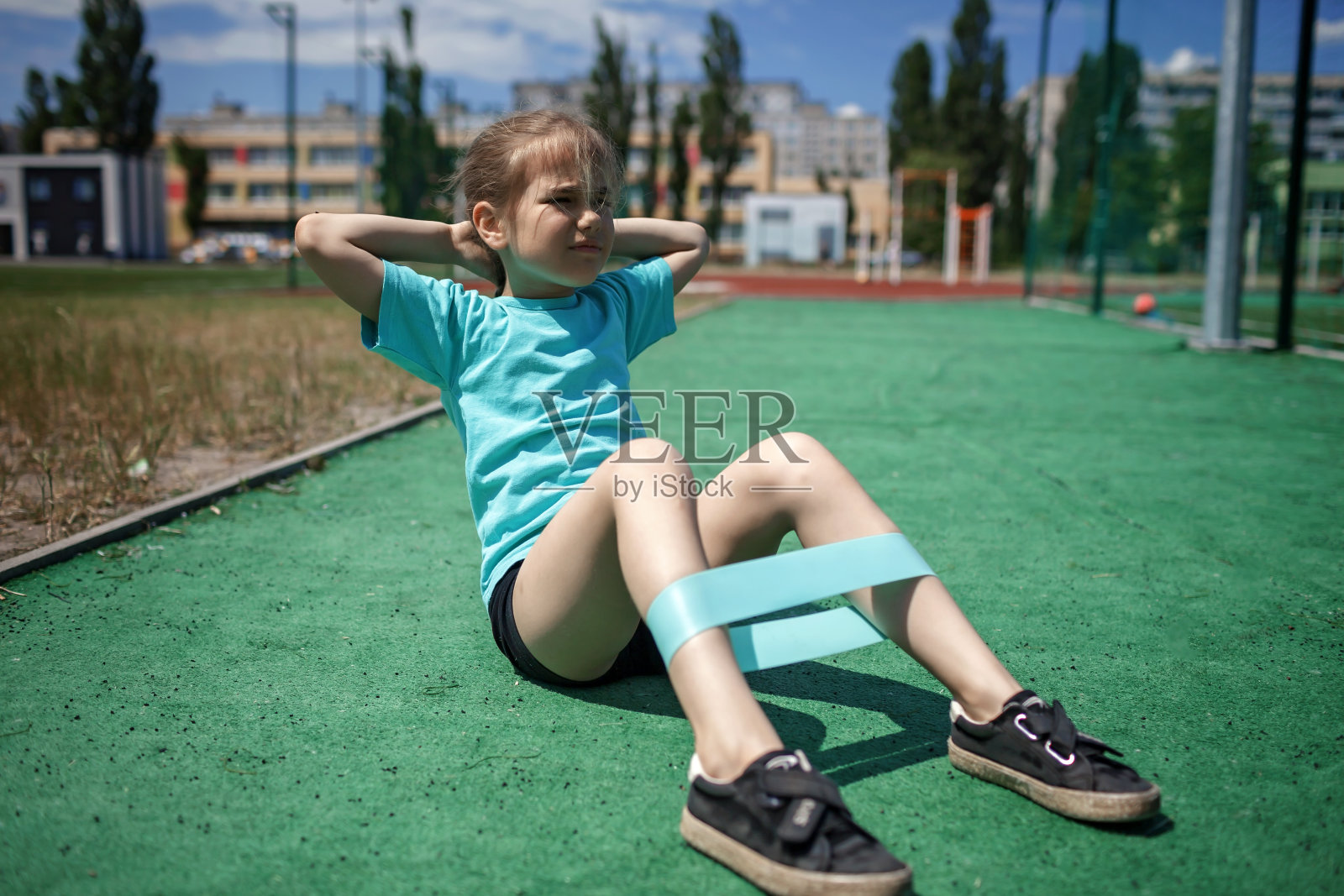 十多岁的女孩在城市的公共运动场用健身阻力带做运动照片摄影图片