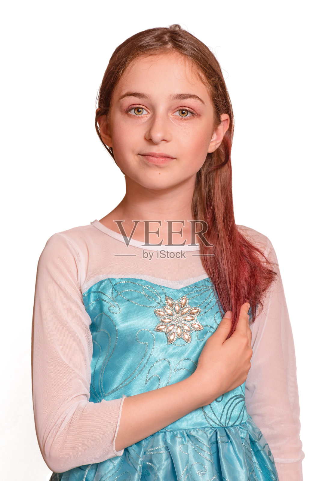 害羞的少女站在那里看着镜头。她穿着一件装饰过的蓝色连衣裙。隔离照片摄影图片