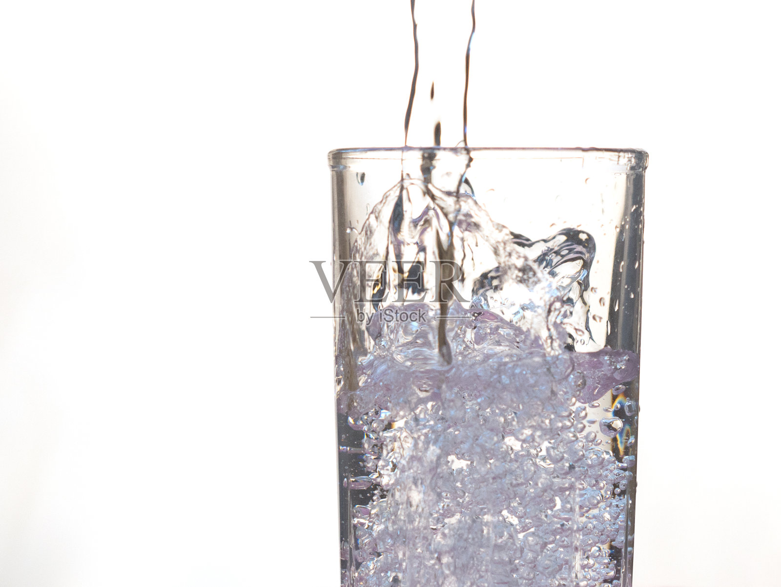 水倒进玻璃杯里。白色背景上的透明饮用水。特写镜头。照片摄影图片