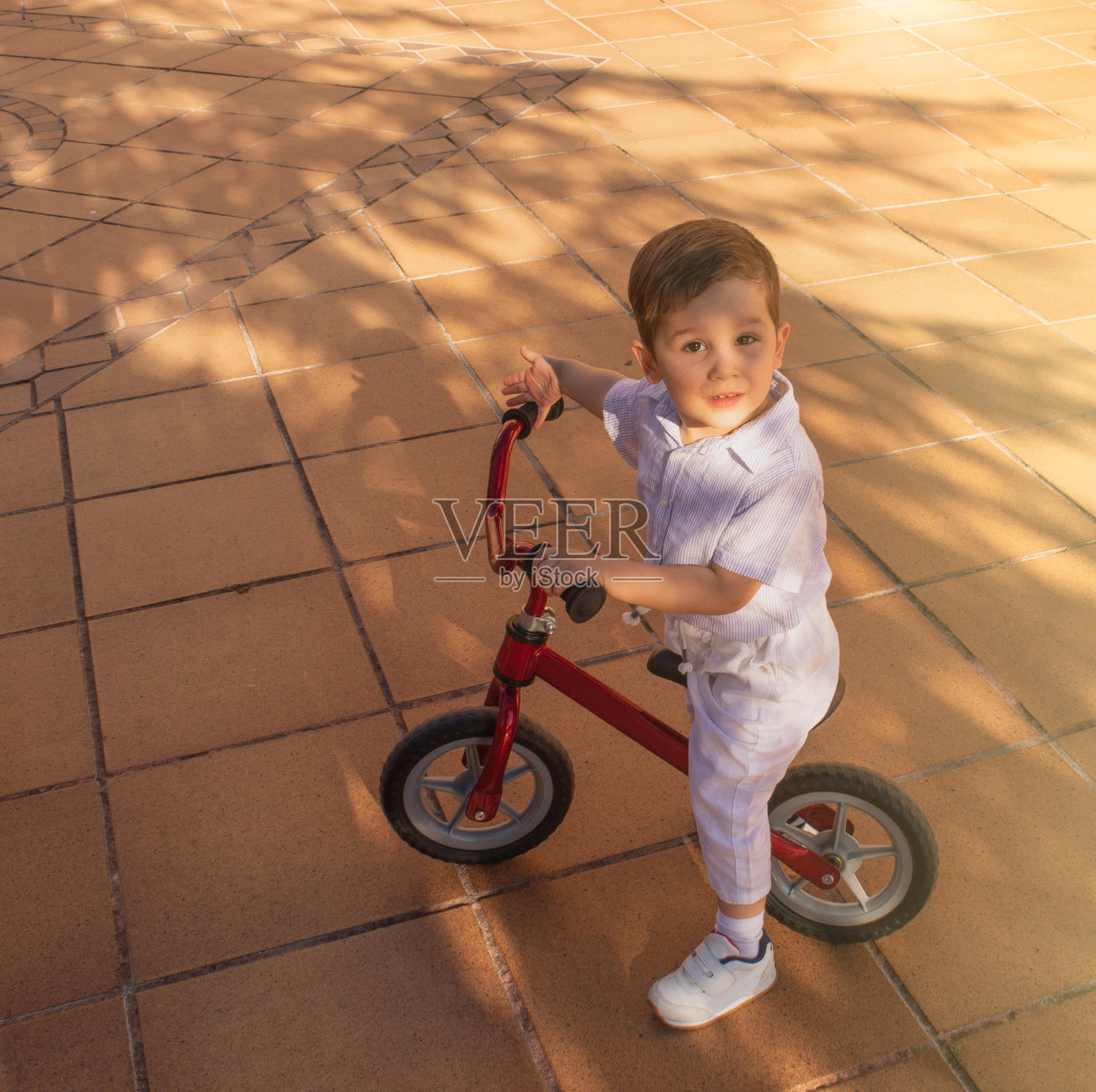 孩子们玩着没有踏板的自行车，学习如何在阳光明媚的日子里骑一辆大自行车照片摄影图片