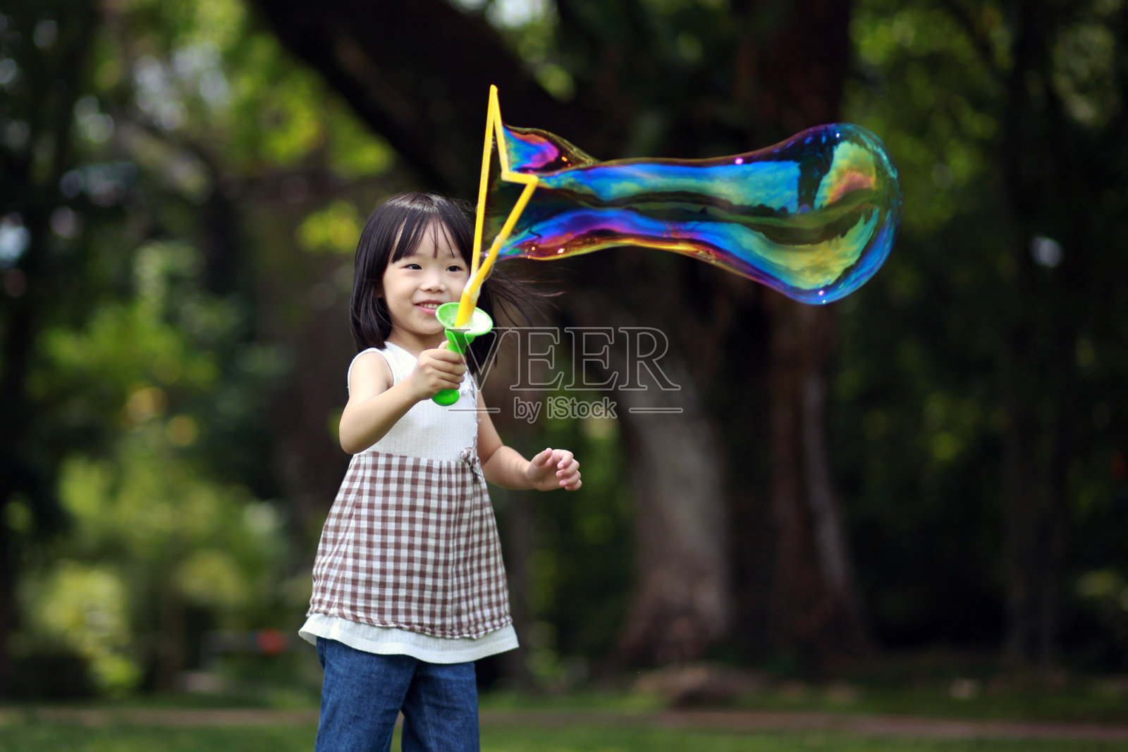可爱的亚洲小女孩在户外的自然公园玩肥皂泡照片摄影图片