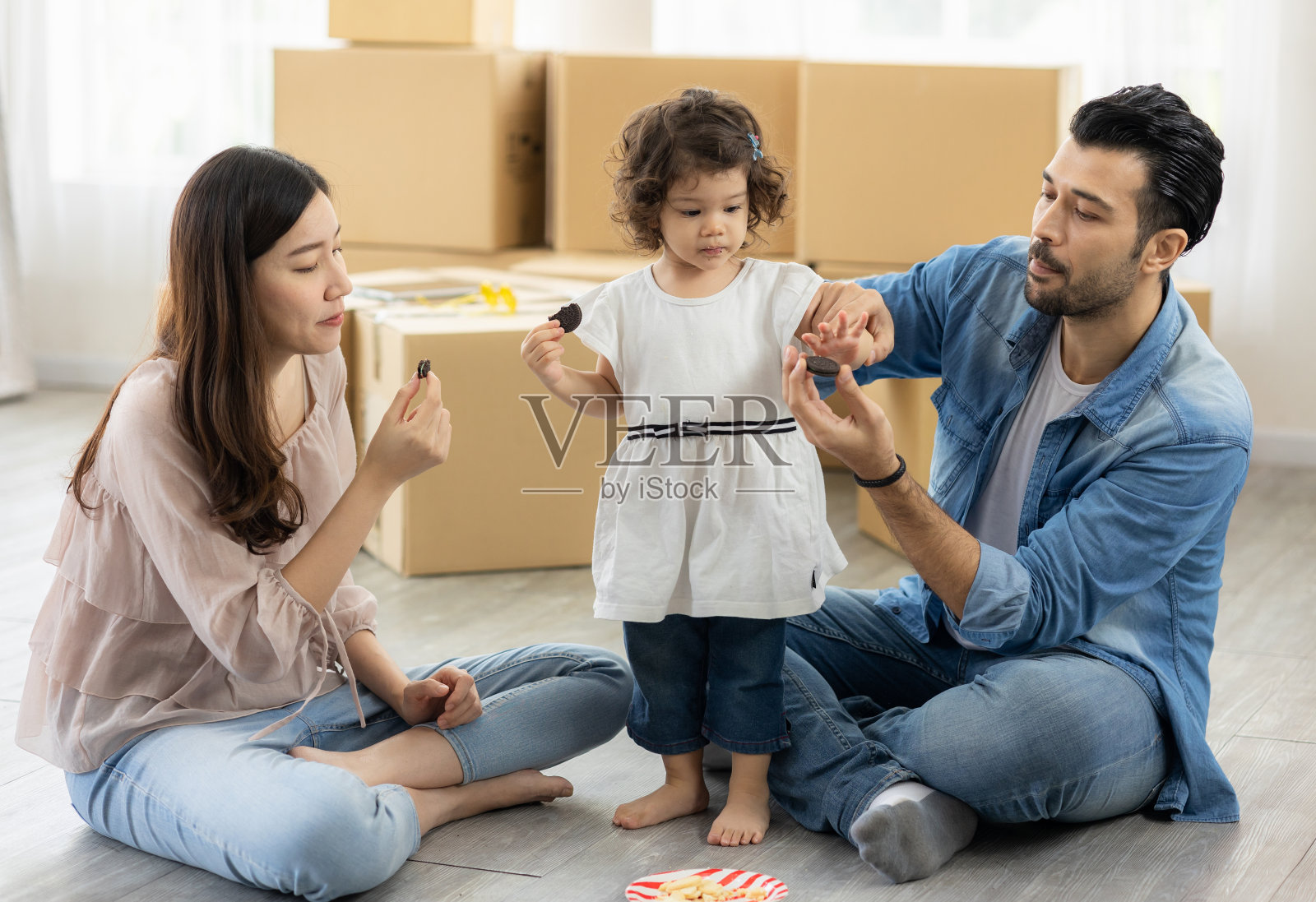 家人在家客厅吃巧克力饼干的快乐时刻。爸爸，妈妈和女儿笑着在早上吃一顿好饭。照片摄影图片
