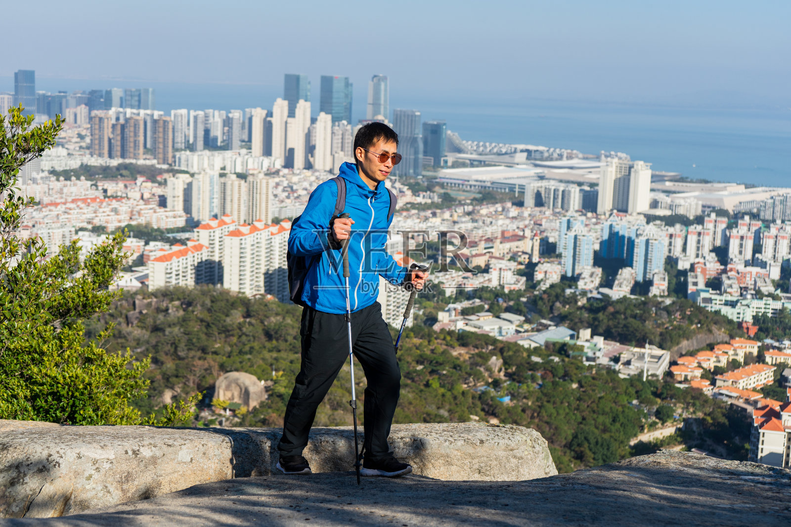 一名亚洲男子用登山杆向山顶走去照片摄影图片