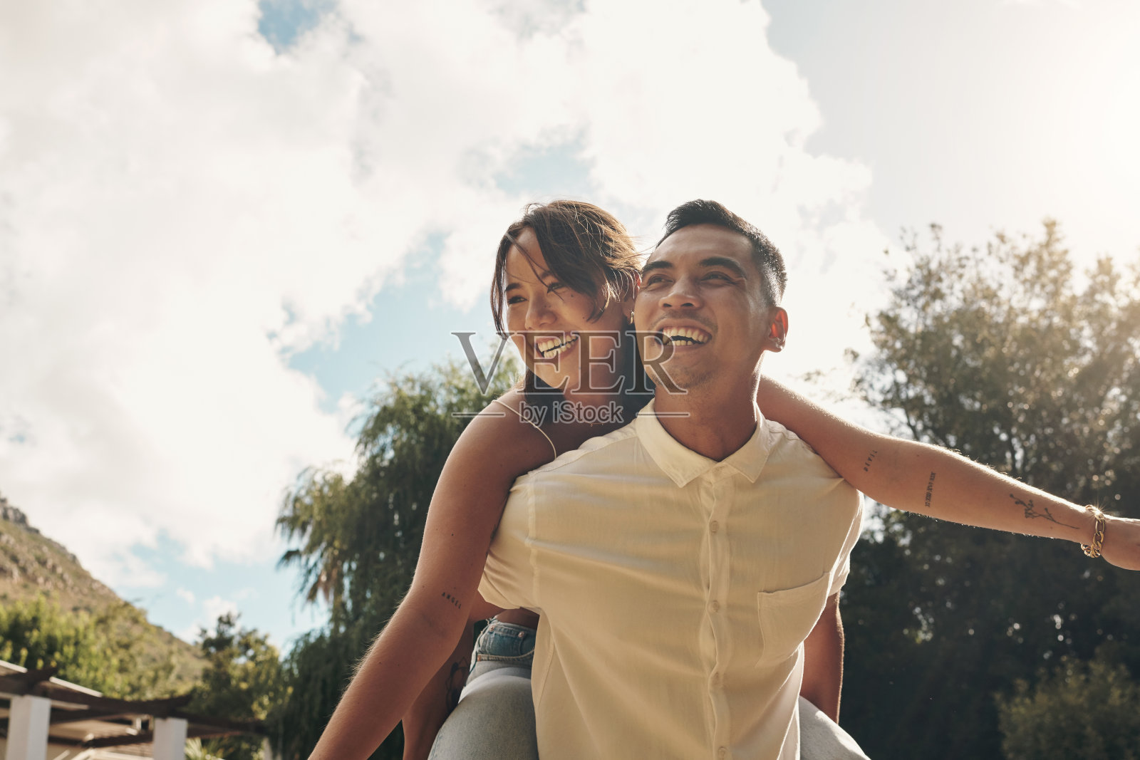 一个英俊的年轻人白天在外面亲热时背着他的女朋友照片摄影图片