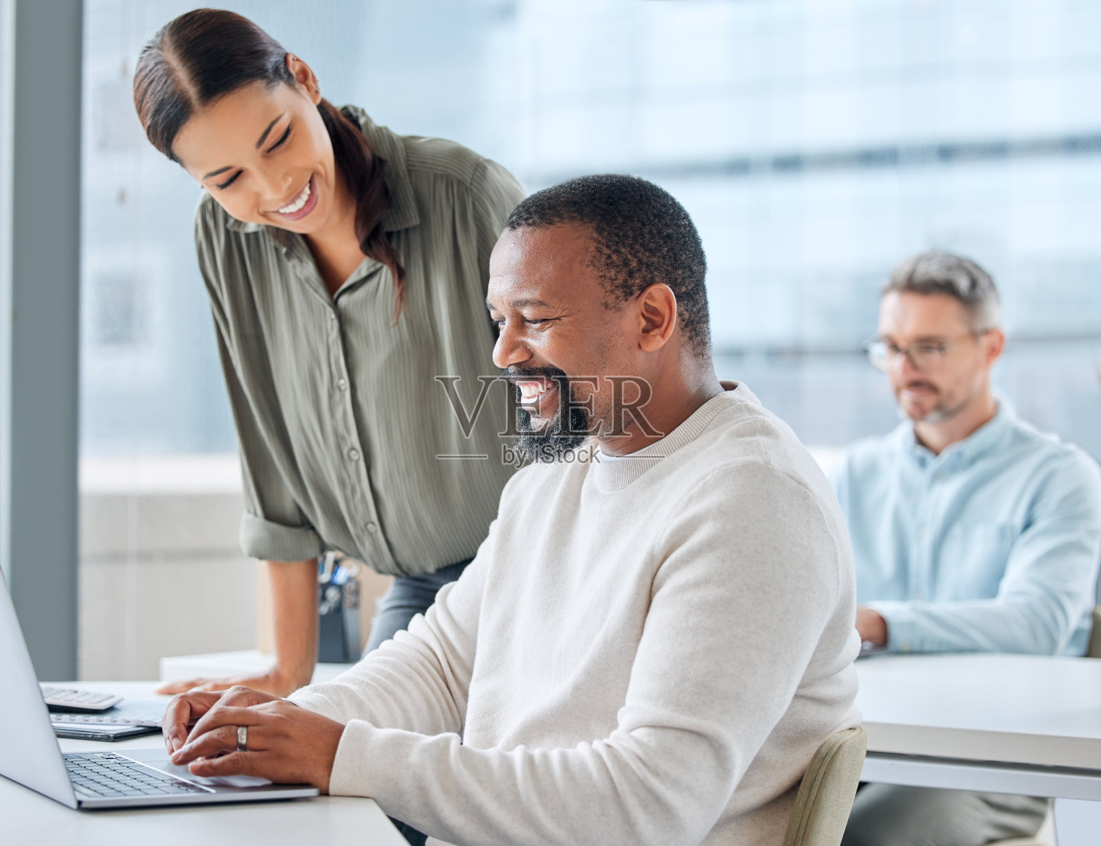 这是两名商人在办公室用笔记本电脑一起工作的照片照片摄影图片