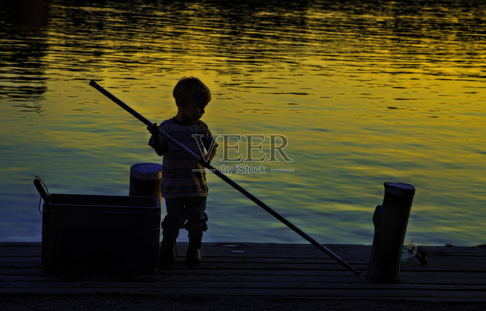 小男孩在水边。日落。夏天宁静的athmosphere。照片摄影图片