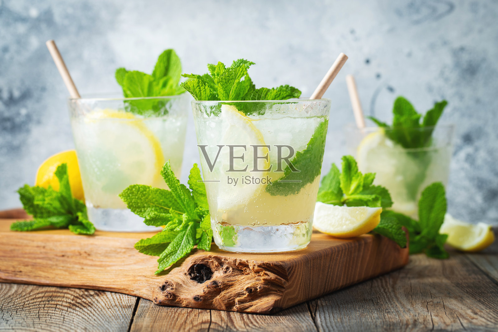 两杯柠檬水或莫吉托鸡尾酒，柠檬和薄荷，清凉饮料或饮料与冰在乡村蓝色背景照片摄影图片