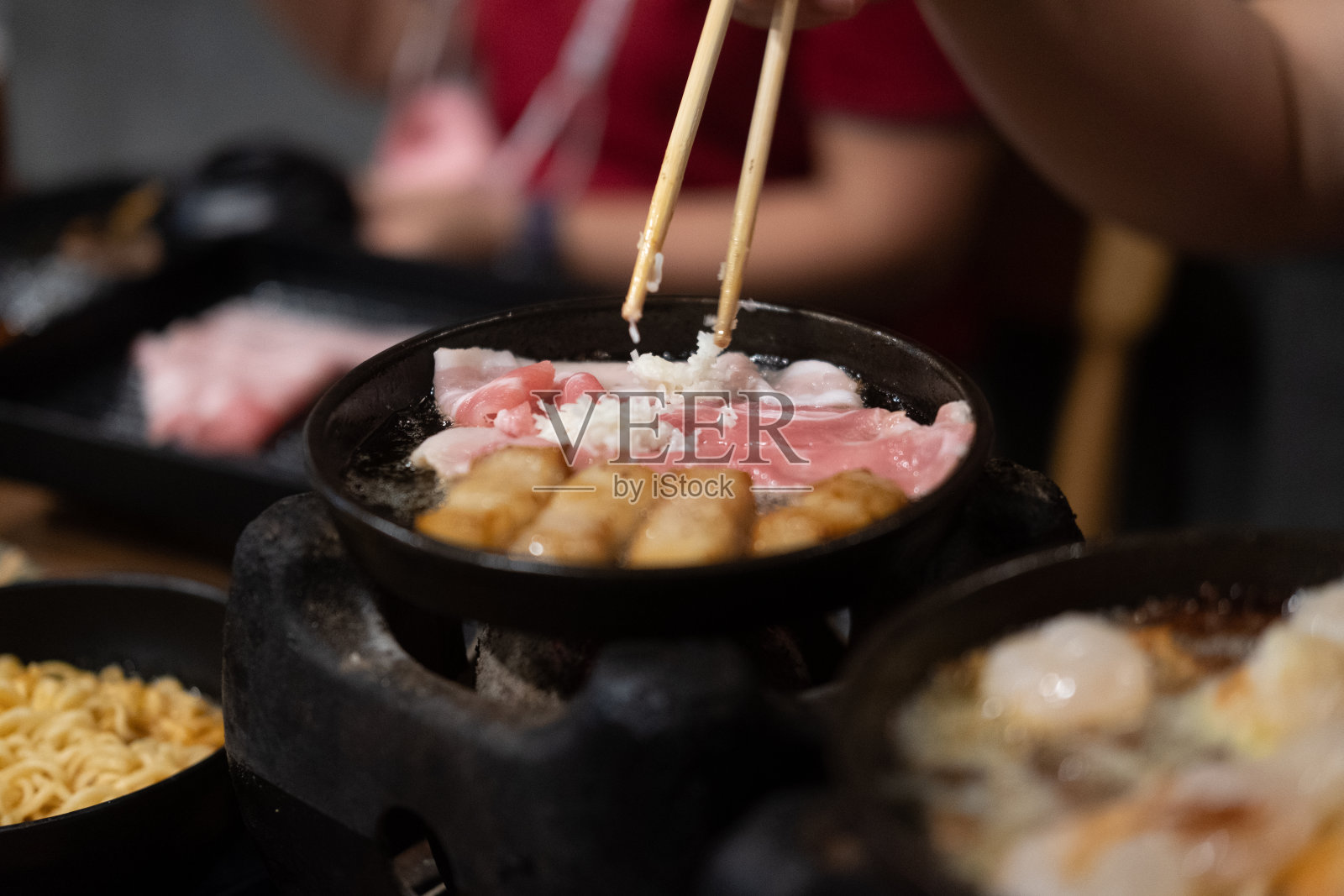 手正在用筷子烧烤猪肉。有选择性的重点照片摄影图片