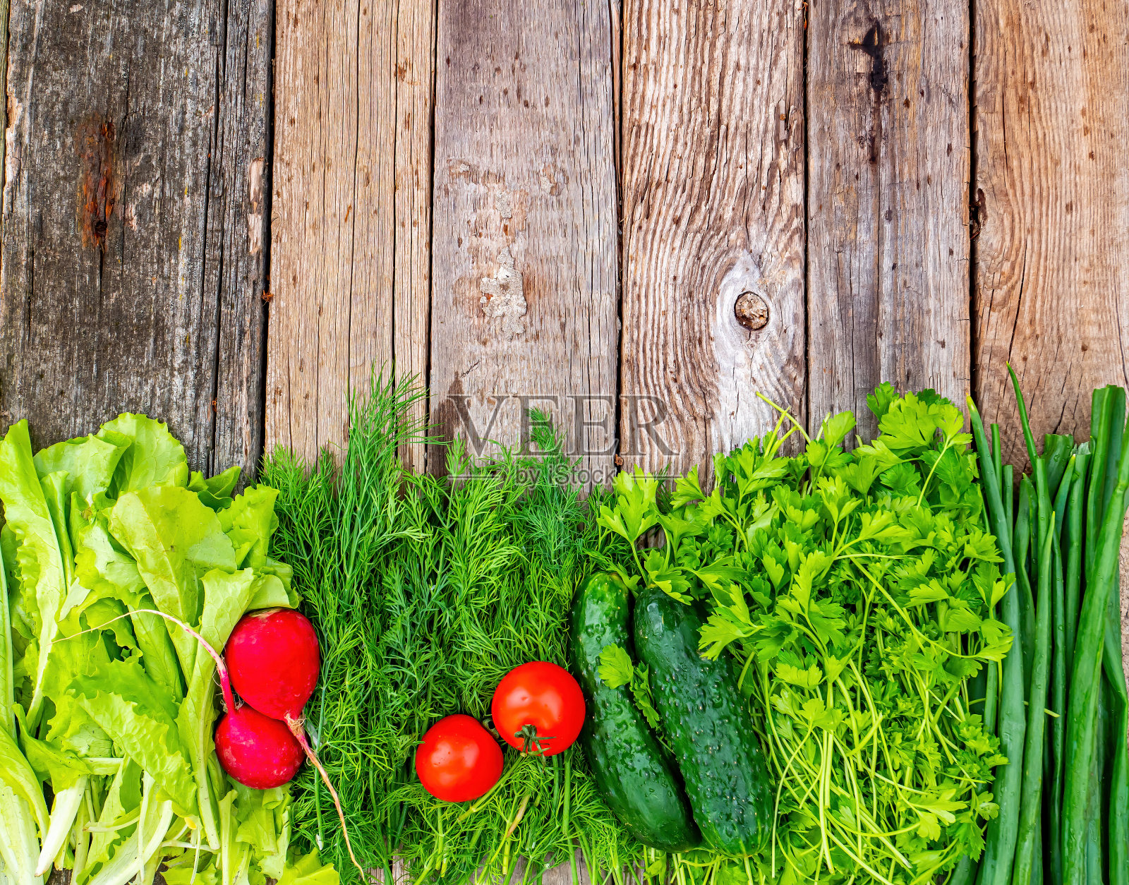 蔬菜，黄瓜，西红柿和萝卜放在一张木桌上。照片摄影图片