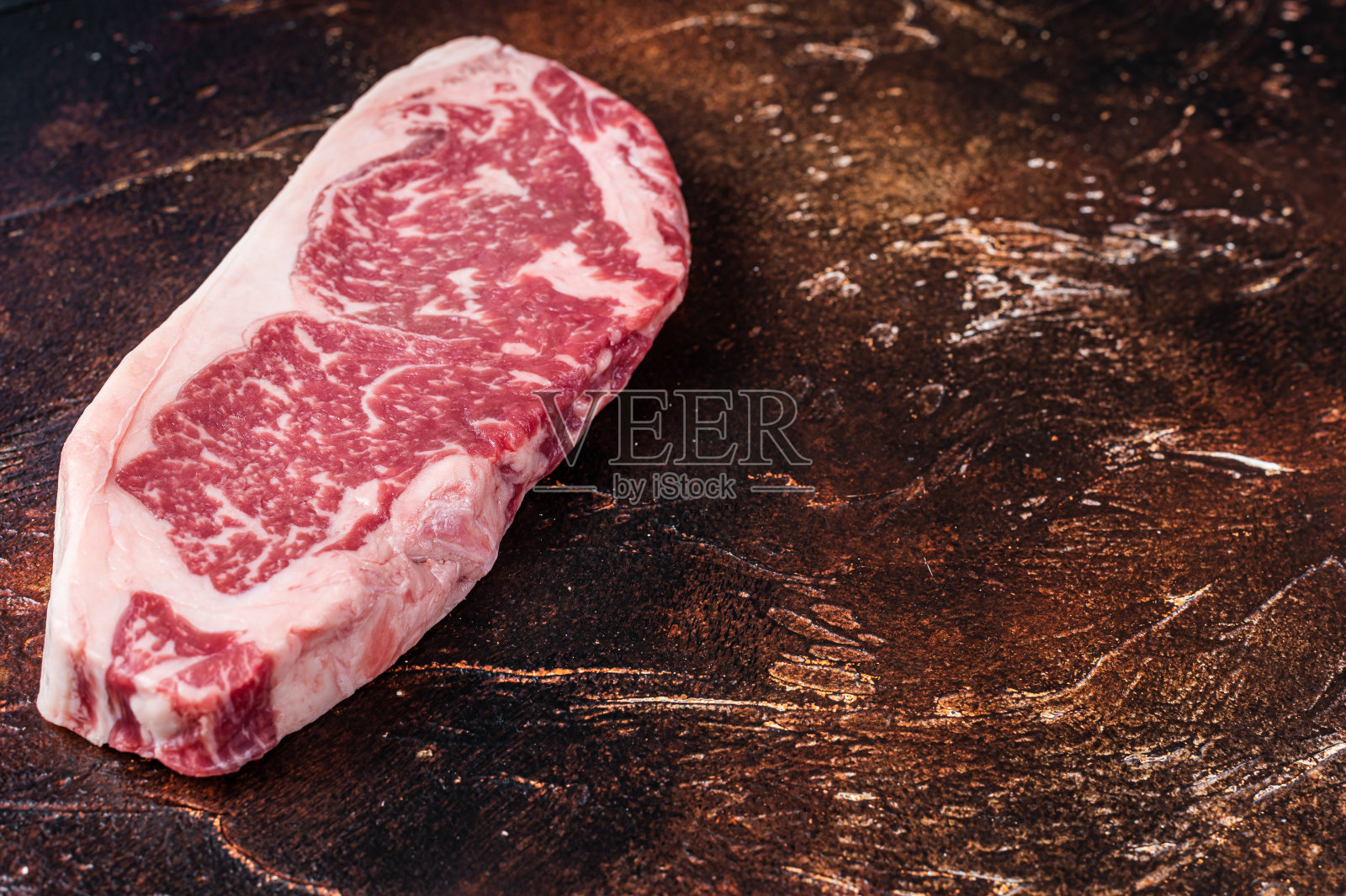 生的纽约牛排或striploin在屠夫桌上。黑暗的背景。前视图。本空间照片摄影图片