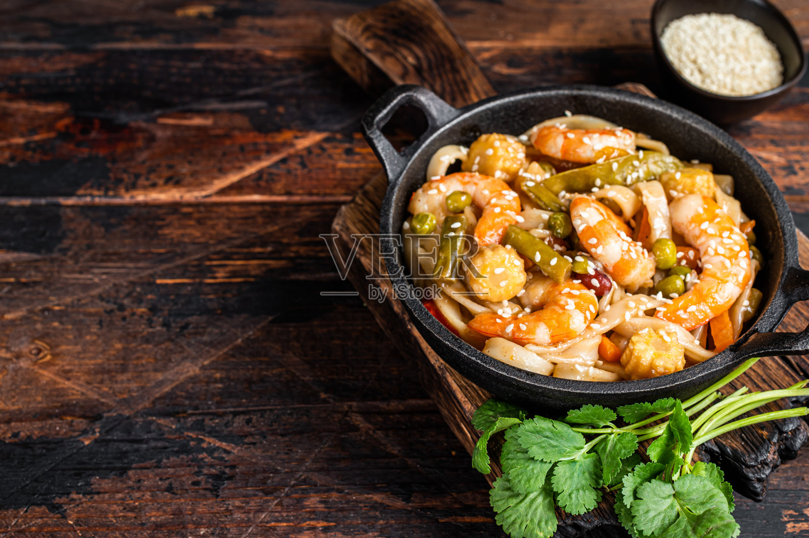 亚洲乌冬炒虾面与虾在平底锅。深色木制背景。前视图。本空间照片摄影图片