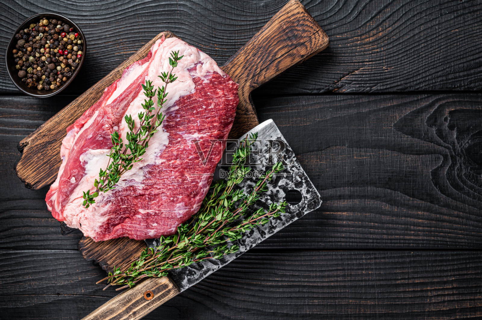 用切肉刀在切肉板上切成的圆形烤牛肉。黑色木制背景。前视图。本空间照片摄影图片