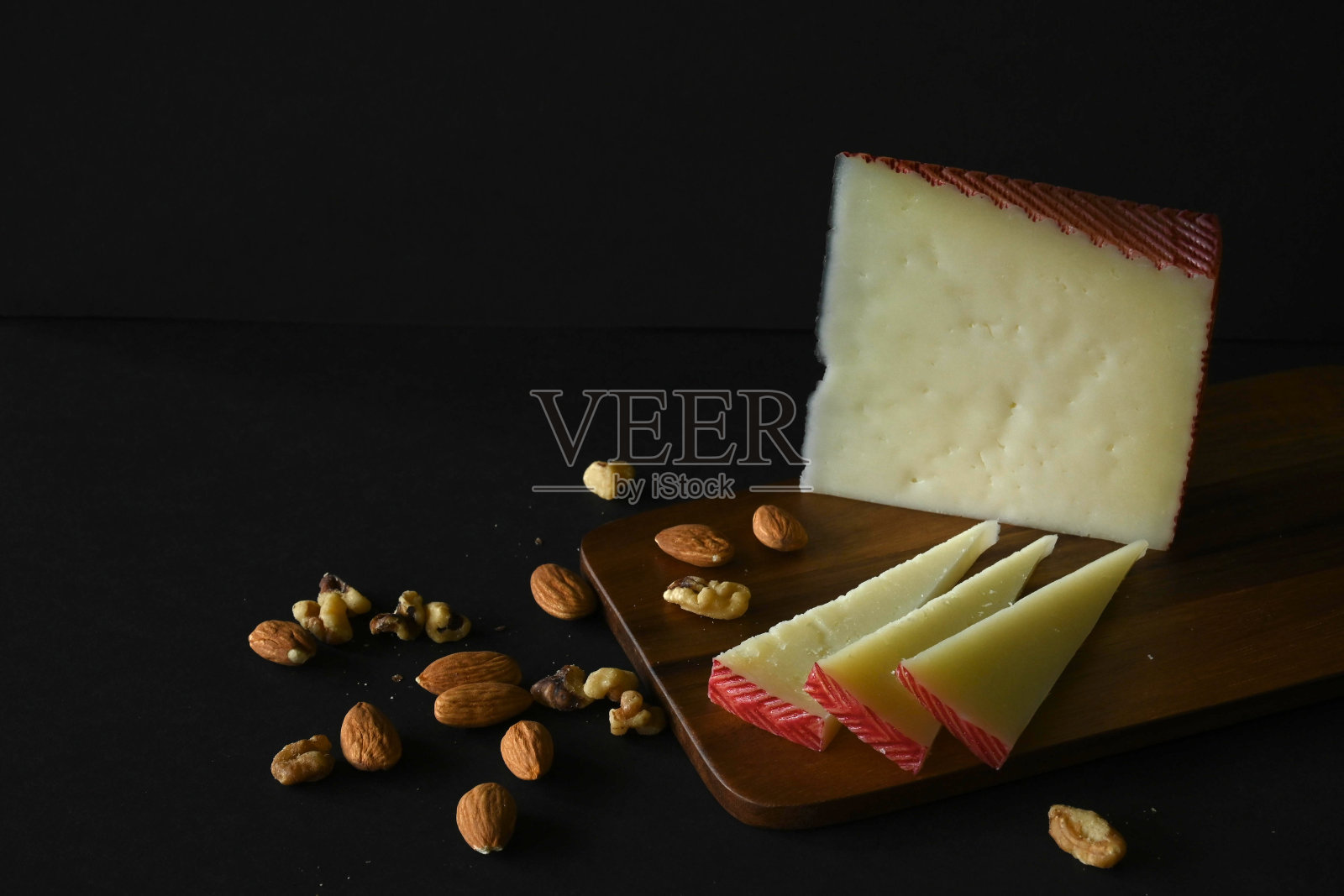 水平特写曼彻格奶酪与核桃和杏仁切板，黑色背景，复制空间照片摄影图片