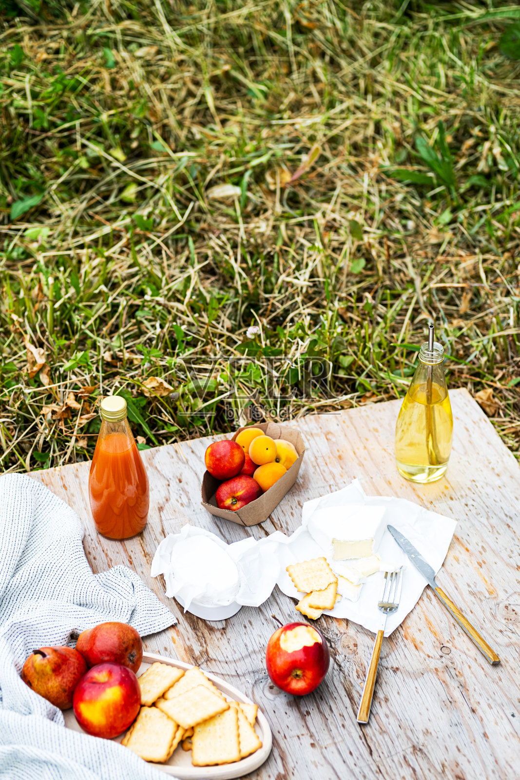 雨天的乡村野餐。各种水果、饮料、奶酪放在带有雨滴的木桌上。夏季周末或假期概念。照片摄影图片