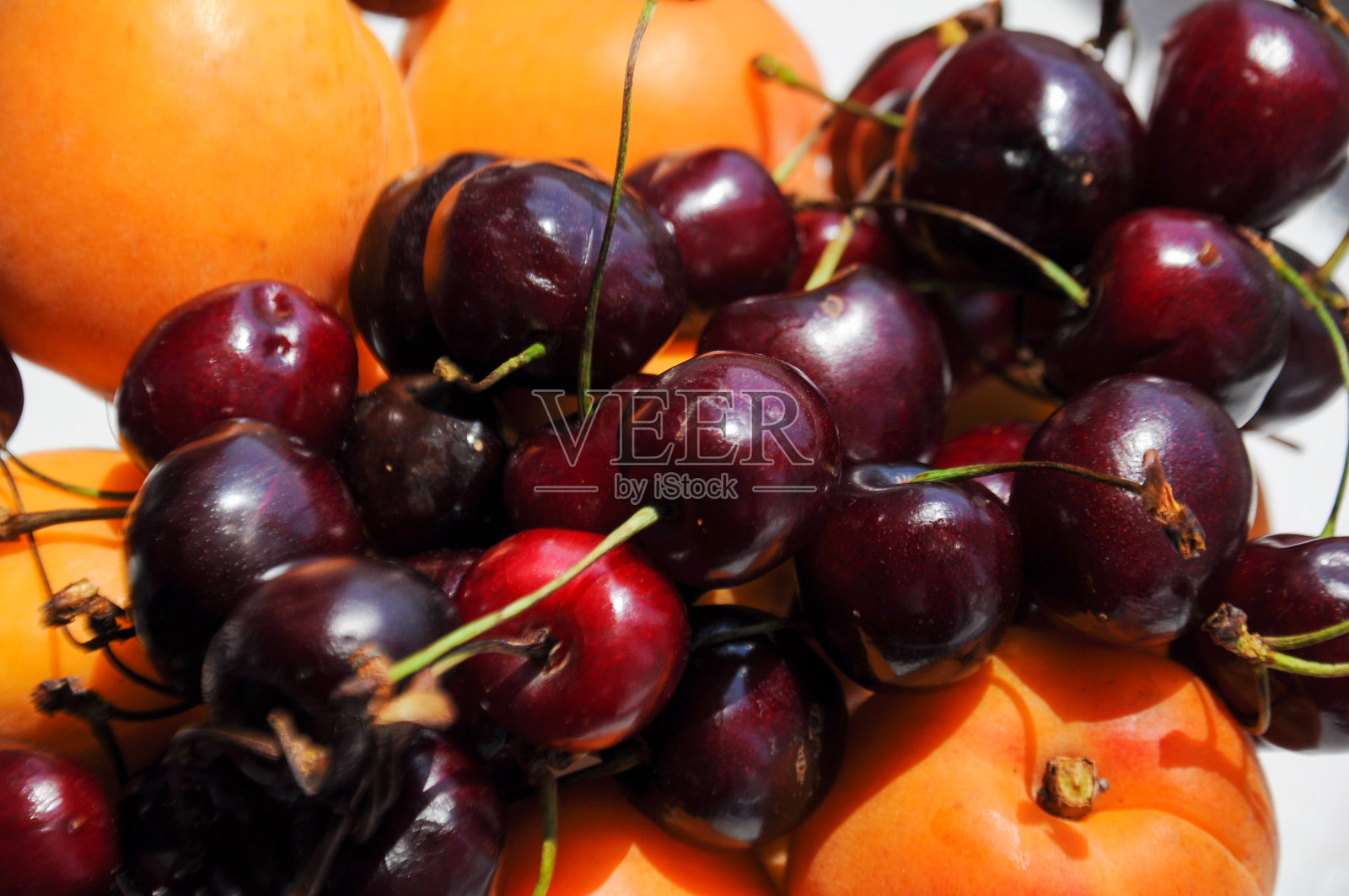 玻璃碗里装着红樱桃和杏子照片摄影图片