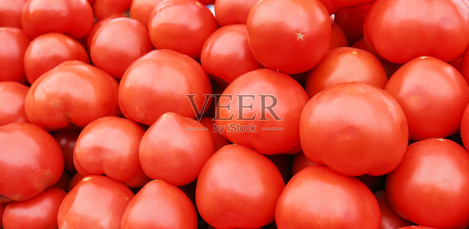 在集市上，一个女人手里拿着西红柿。照片摄影图片