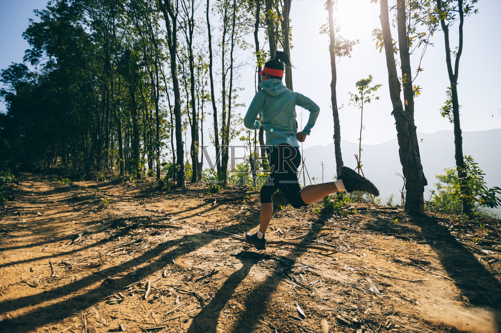 健身女子越野跑在日出热带森林山顶照片摄影图片