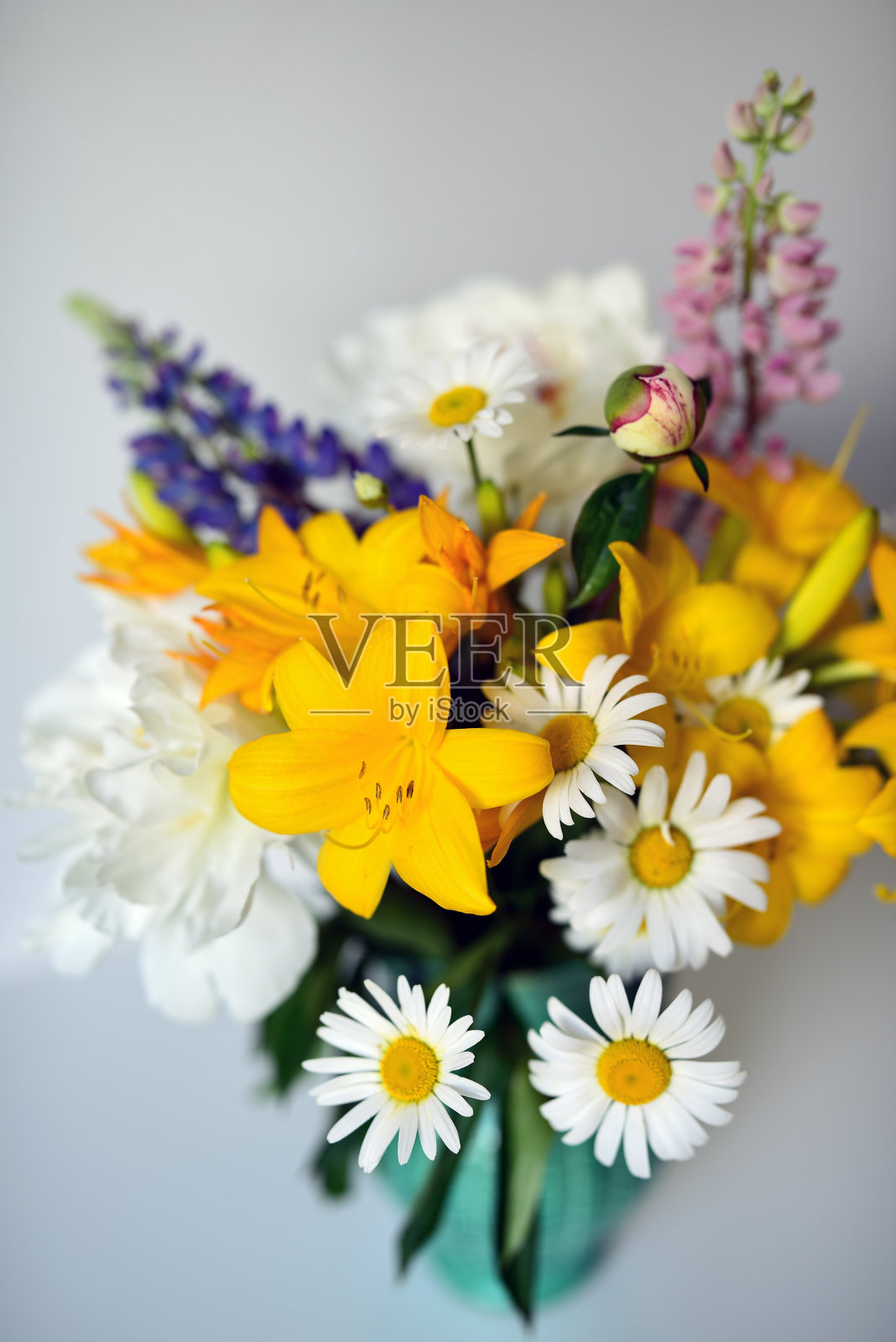 靠墙的白色桌子上放着一束夏天的花园和野花。照片摄影图片