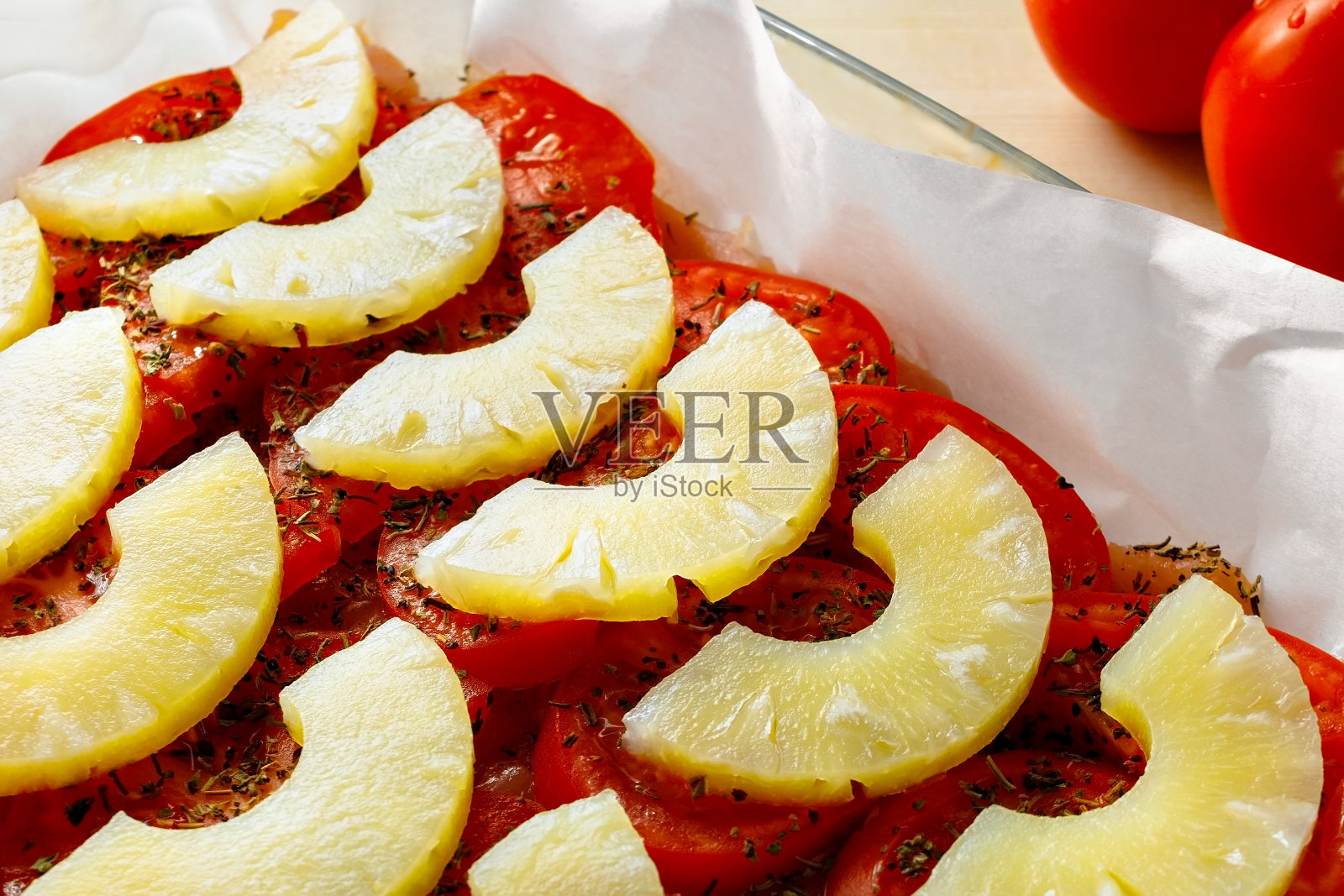 蔬菜和水果在食物中的组合。用西红柿煮菠萝。一种可以在家快速烹饪的美味菜肴的食谱照片摄影图片