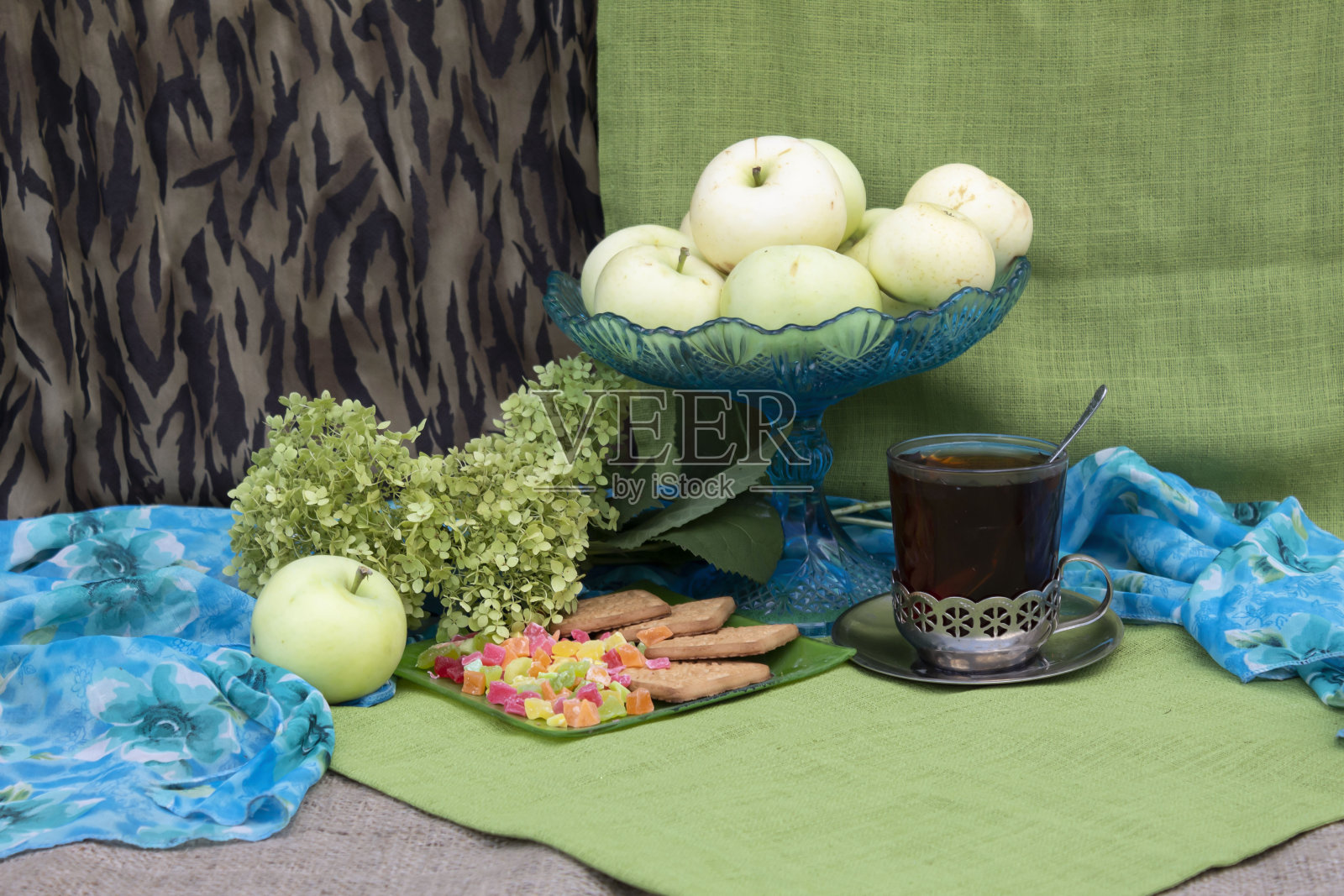 一杯装着苹果和绣球花的茶杯。照片摄影图片