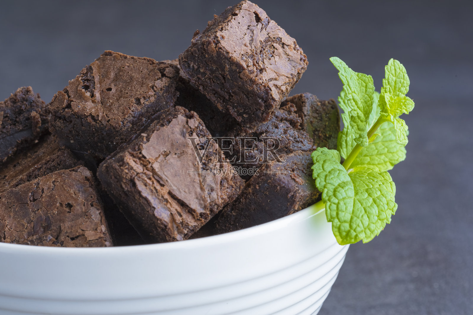 布朗尼方块放在一个白色的碗里，一块薄荷，照片摄影图片