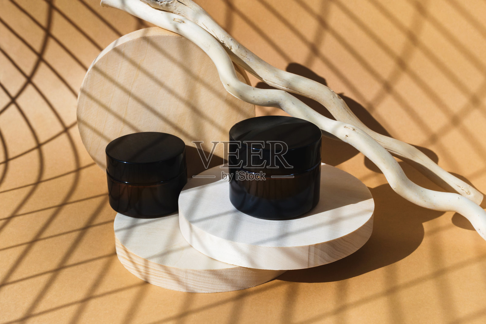 木制讲台上放着两个化妆霜罐，米色背景。现代天然美容产品。照片摄影图片