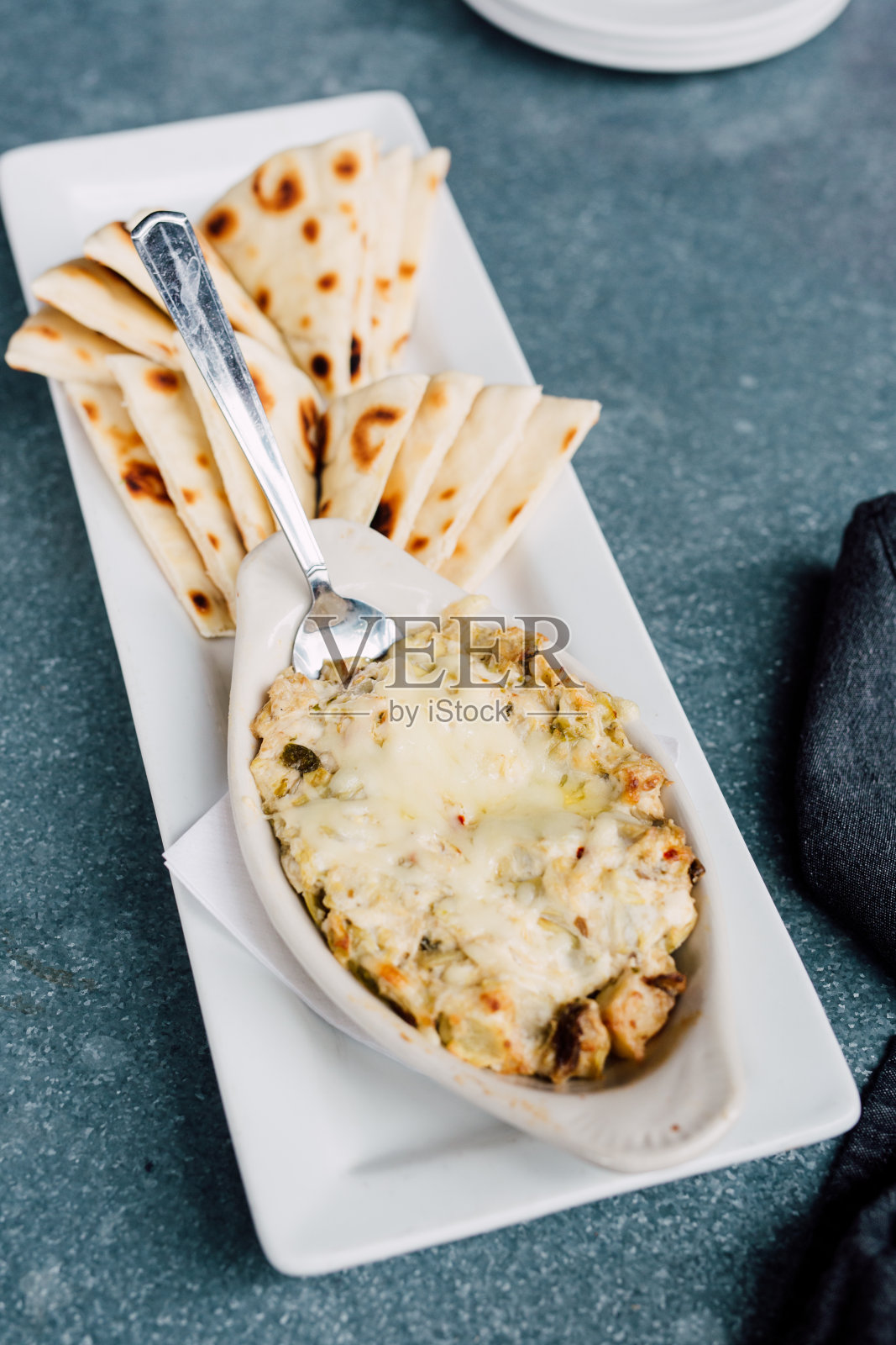 油炸玉米饼周围的小花园沙拉与辣酸奶蘸酱烤皮塔饼和朝鲜蓟奶酪蘸酱照片摄影图片