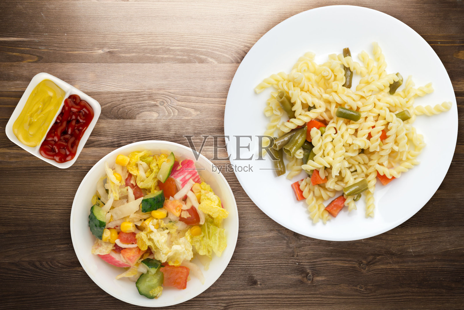 木质背景的白色盘子上放着四季豆、大蒜和胡萝卜意大利面。地中海厨房。照片摄影图片