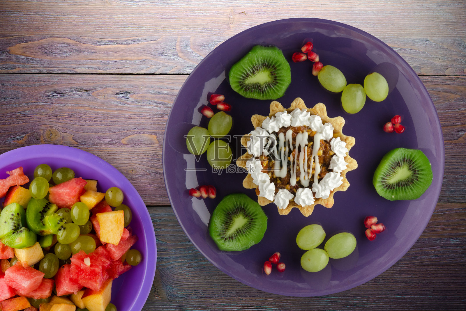 以蛋糕、葡萄、猕猴桃、石榴为背景的甜点。照片摄影图片