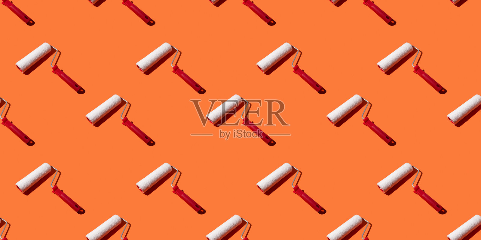 用于在橙色背景、图案、硬阴影上绘画的滚轴。施工工具,维修。设计背景。照片摄影图片