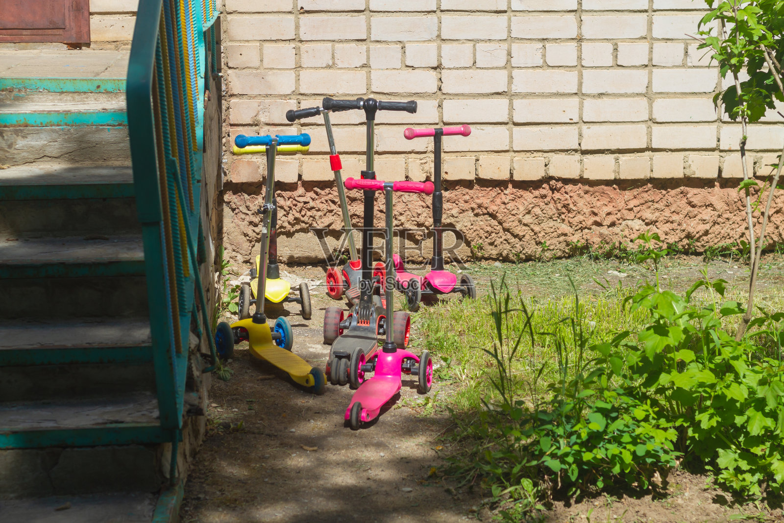 孩子们的滑板车停在幼儿园门口，孩子们骑着五颜六色的滑板车来了照片摄影图片