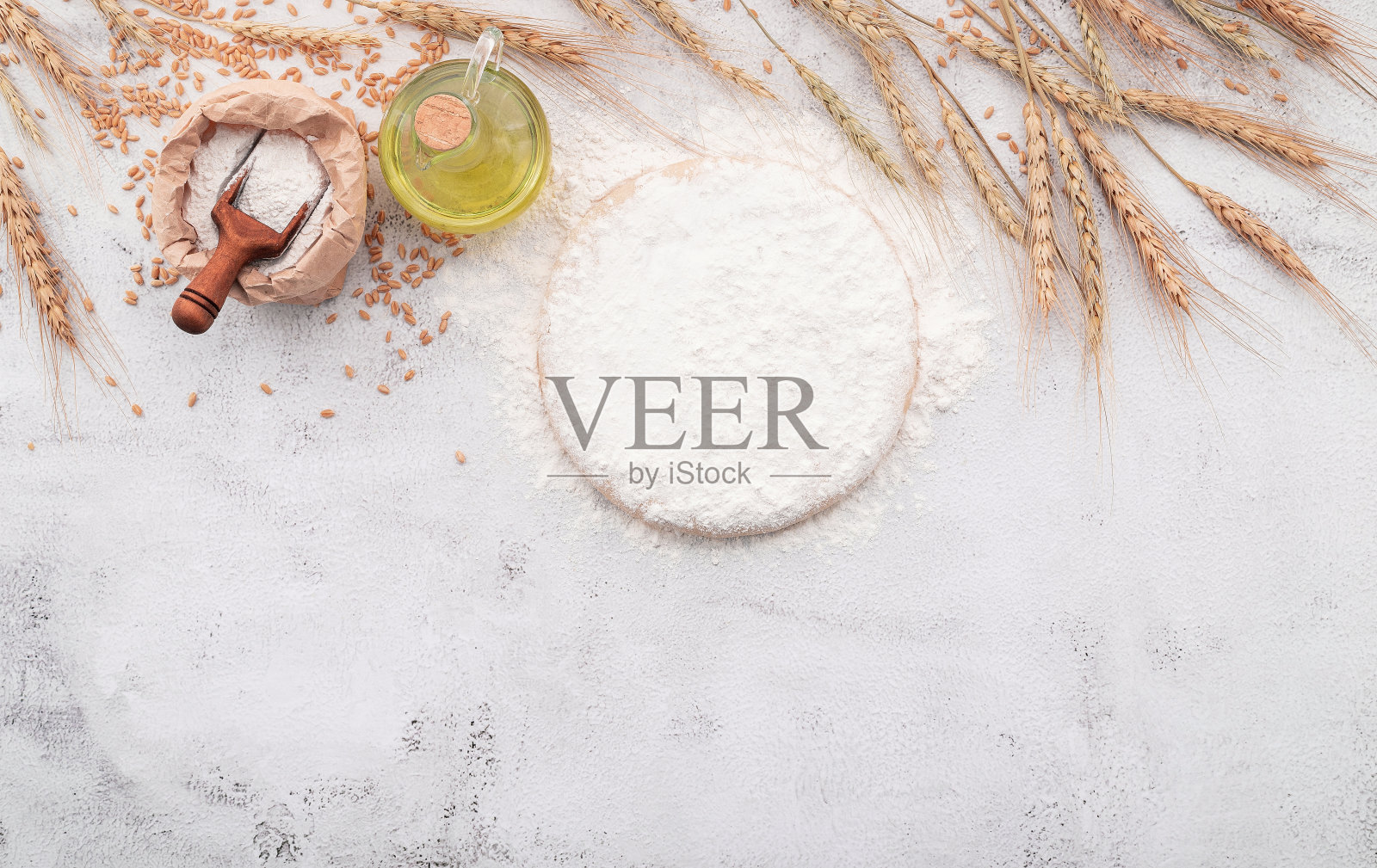 自制披萨面团的原料由小麦穗子、小麦粉和麦粒组成，以白色混凝土为背景。照片摄影图片