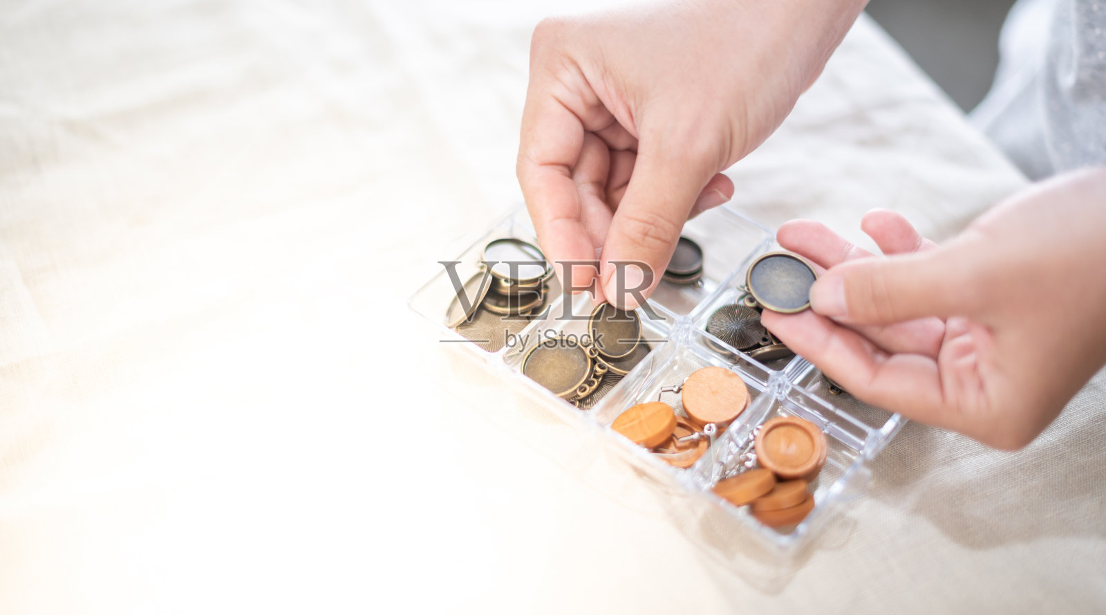 女性手捧并选择金属板框耳环或挂件为绣花线照片摄影图片