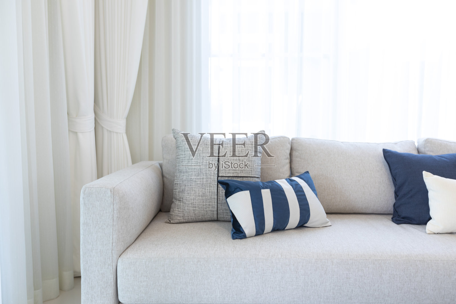 现代的客厅内部，白色的长沙发和蓝色的枕头。照片摄影图片