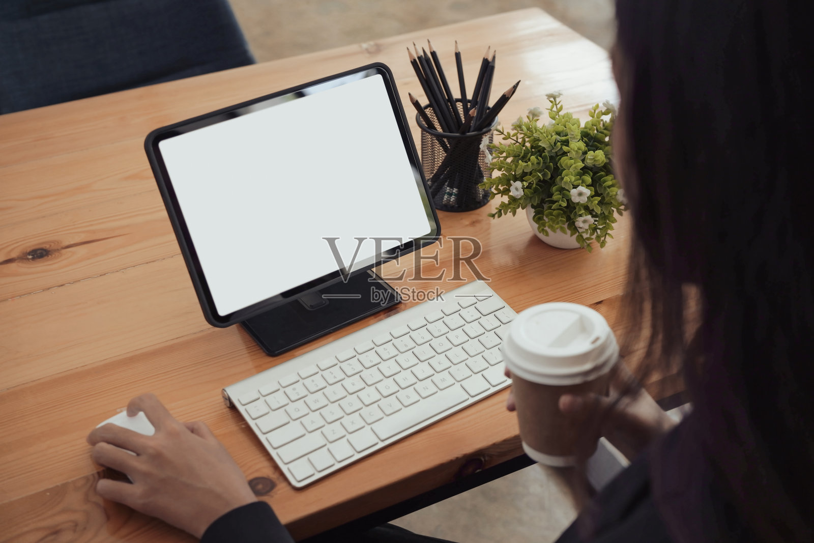 越过女商人的肩膀，拿着咖啡杯和电脑工作。照片摄影图片