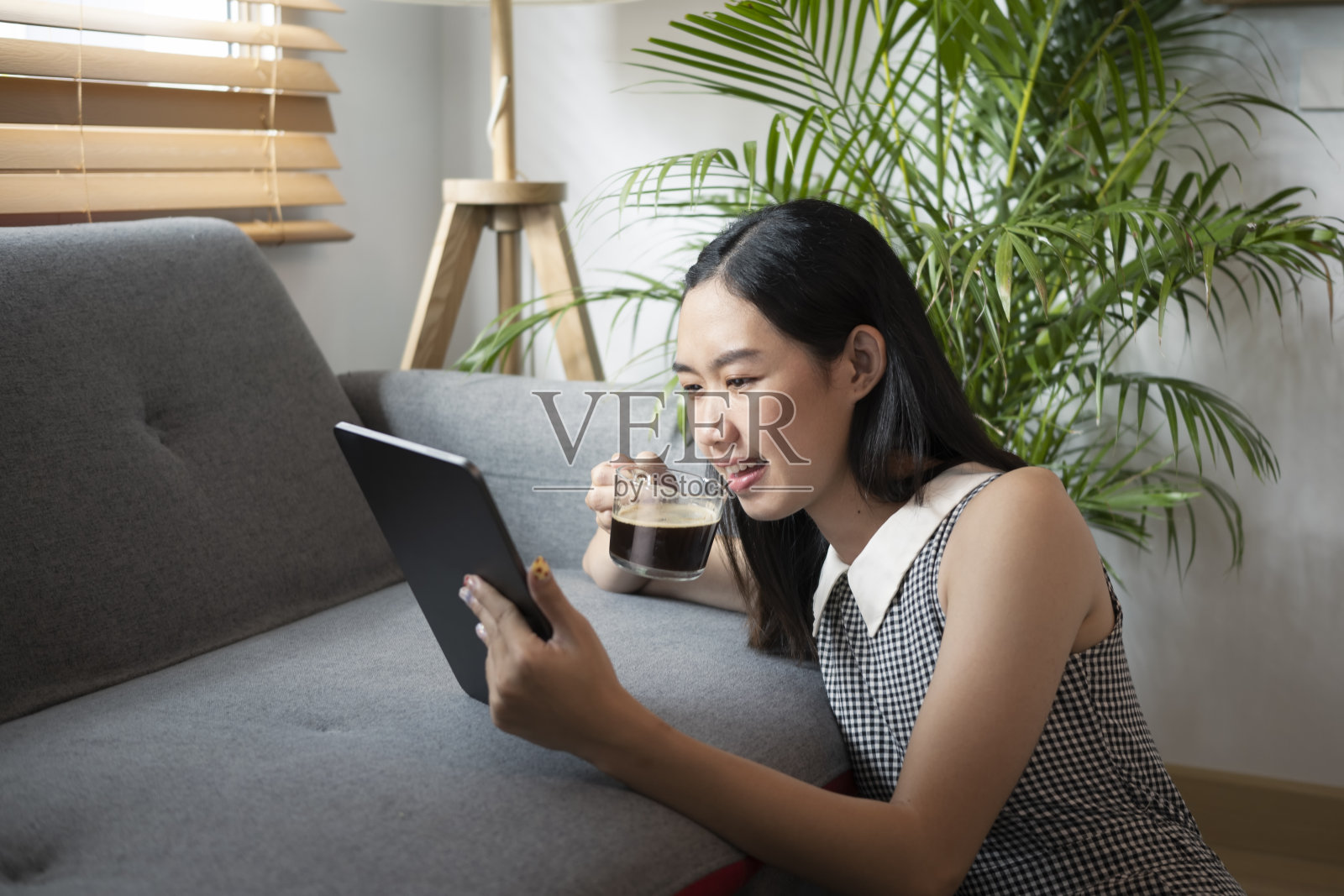 年轻女性喝着咖啡，在平板电脑上查看社交媒体。照片摄影图片