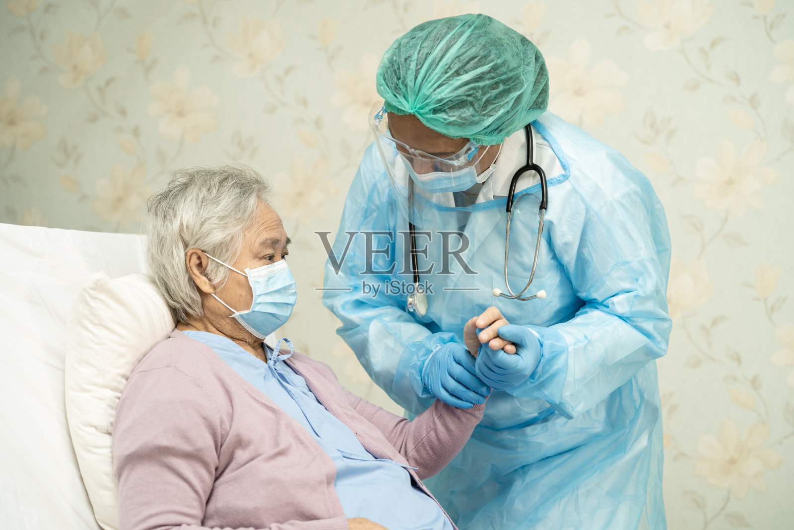 亚洲医生戴口罩和防护服新常态检查患者保护安全感染新冠肺炎疫情在隔离护理医院病房。照片摄影图片