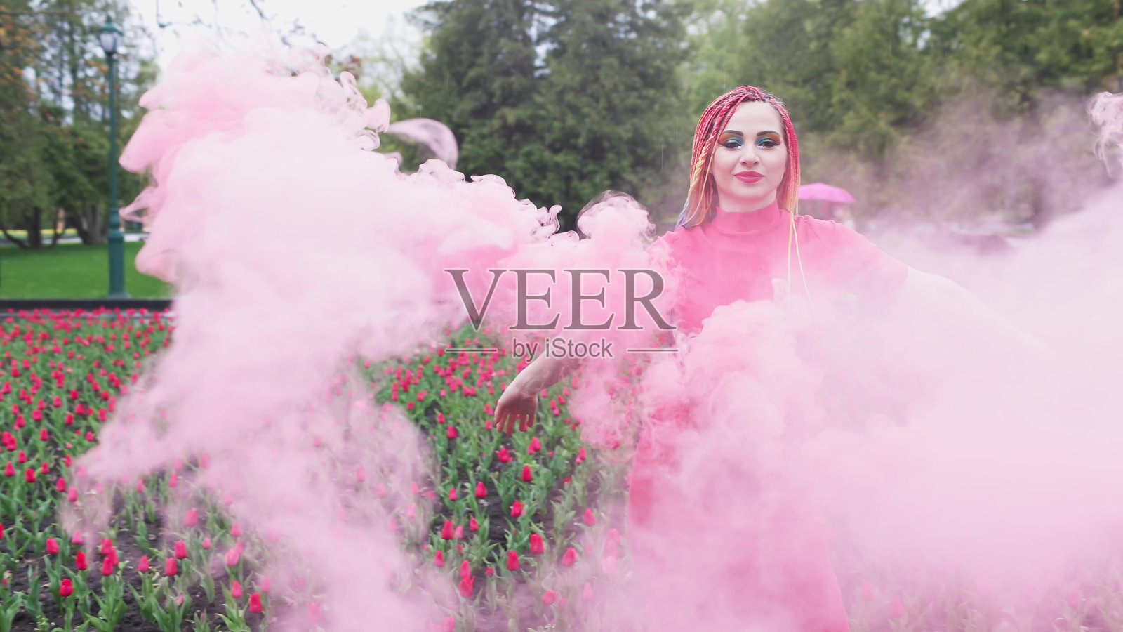 一个女孩带着彩虹辫，穿着红裙子摆姿势照片摄影图片