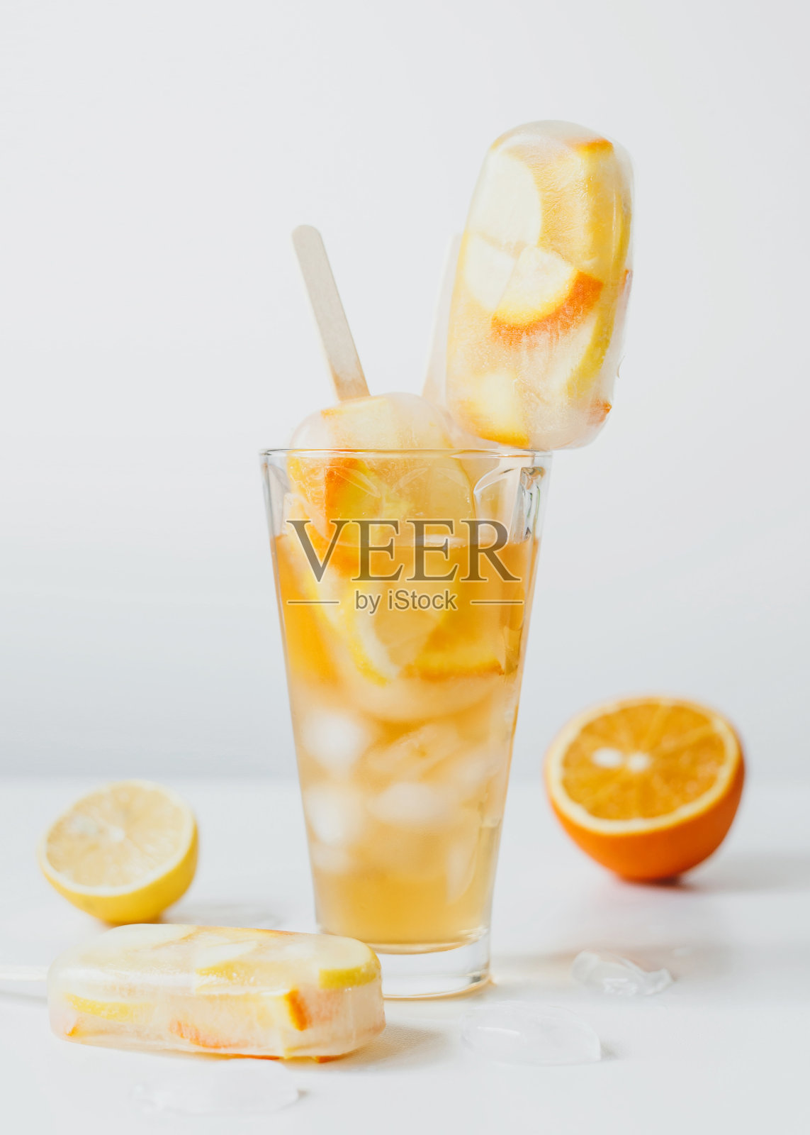 夏季冷饮，柑橘类水果鸡尾酒-橙和柠檬，加冰，和棒冰。照片摄影图片