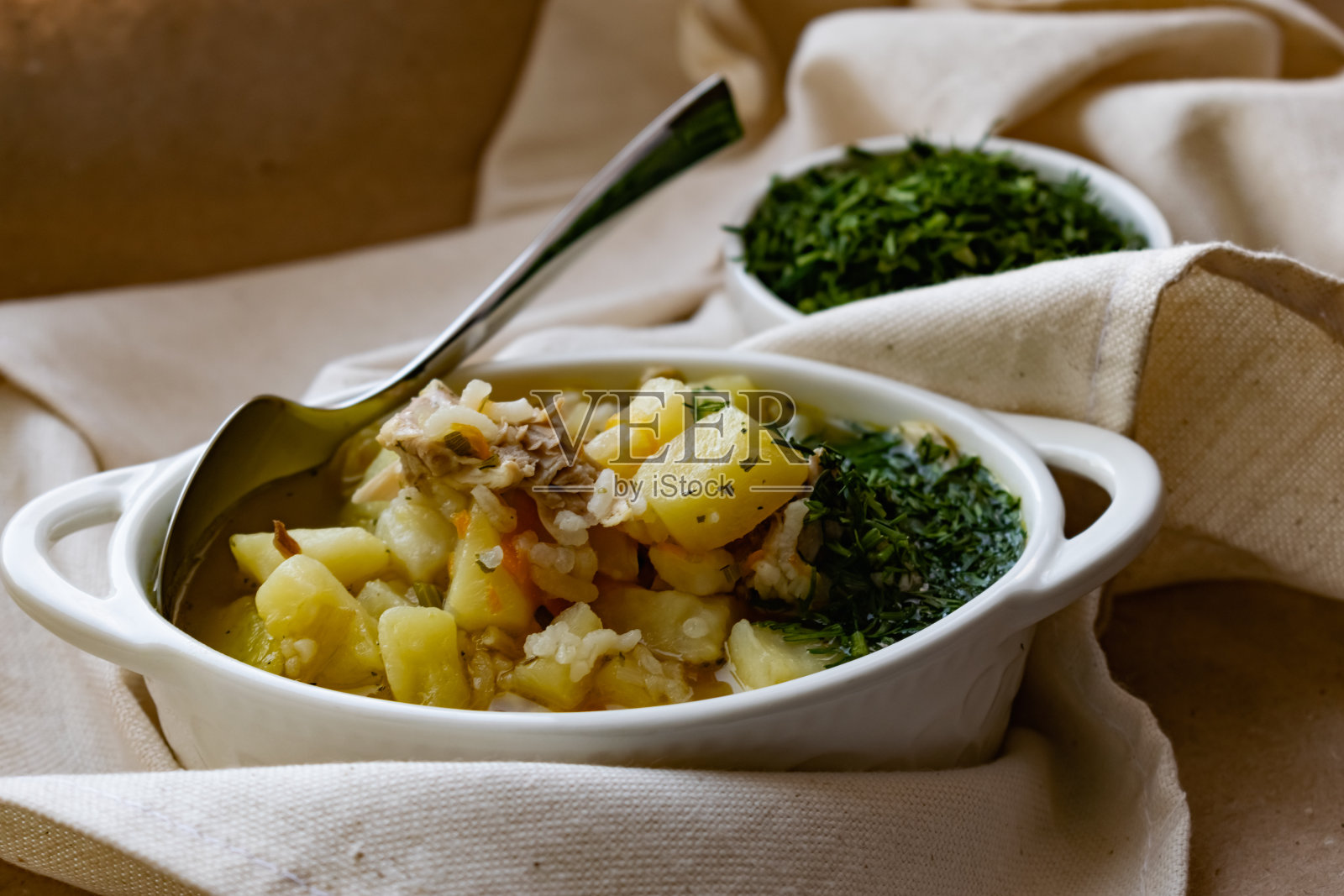 热鸡汤，土豆，肉和新鲜的莳萝在有趣的陶瓷菜肴，在羊皮纸和纺织品照片摄影图片